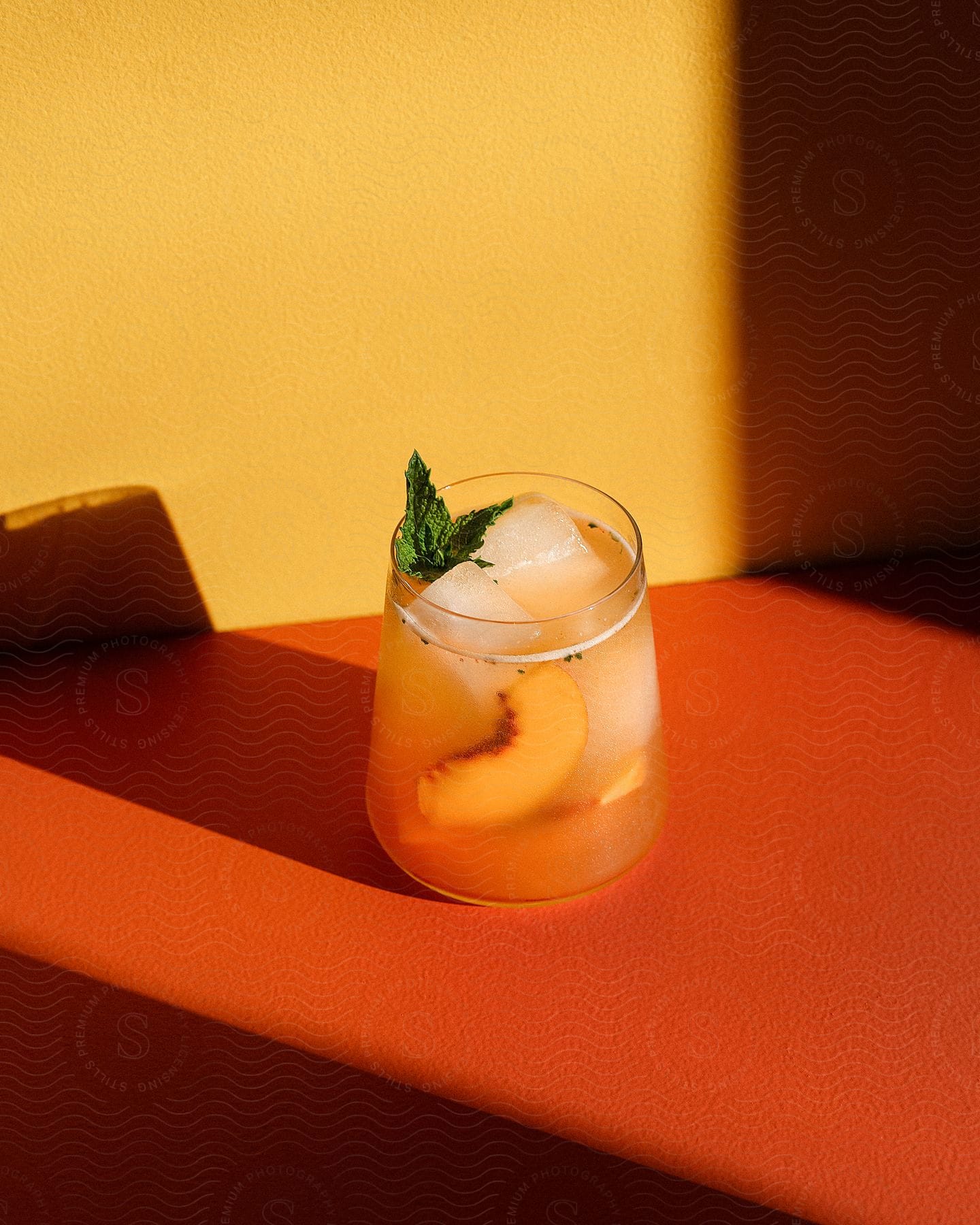 Stock photo of a glass of drink with a piece of fruit and ice cubes.