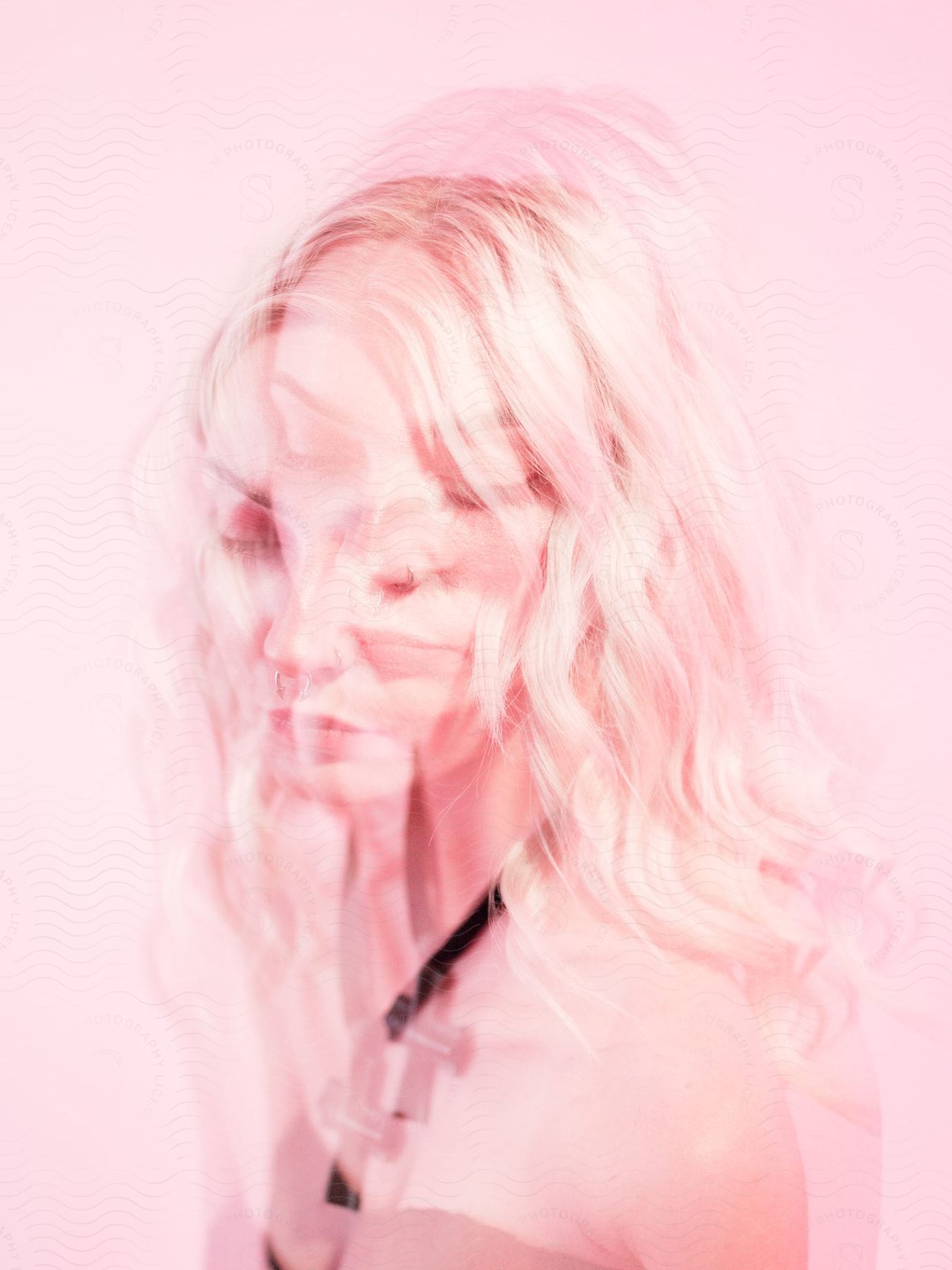 Multiple exposure portrait of a young blonde woman on a pink background.