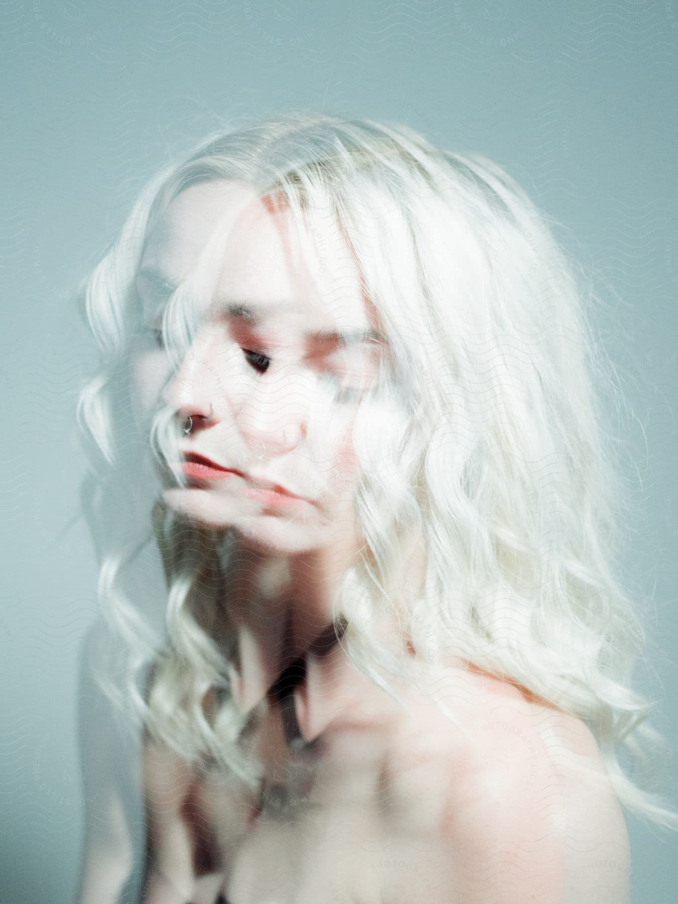 Stock photo of multi exposed close up of pale haired woman in bright lighting.