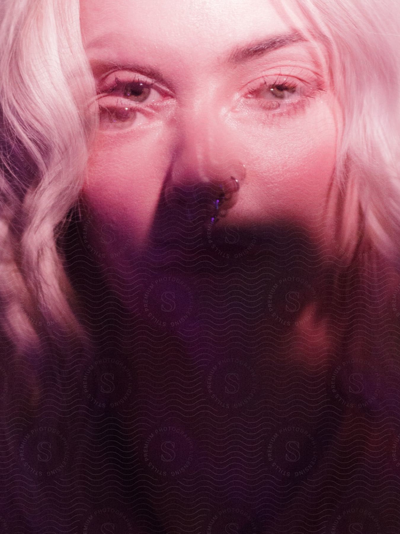 Portrait of a young blonde woman with a nose piercing.