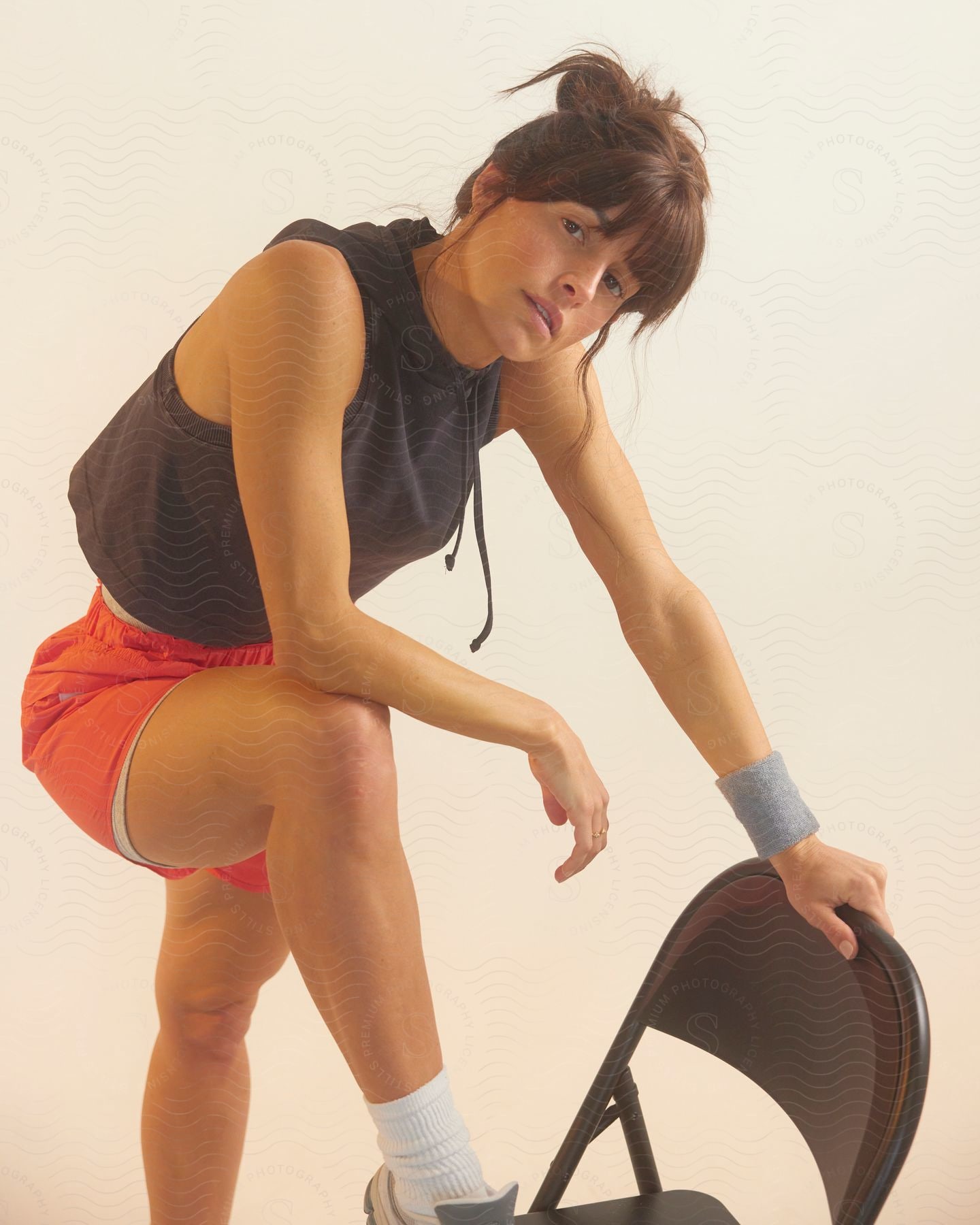 A portrait of a woman wearing exercise gear standing on a chair.