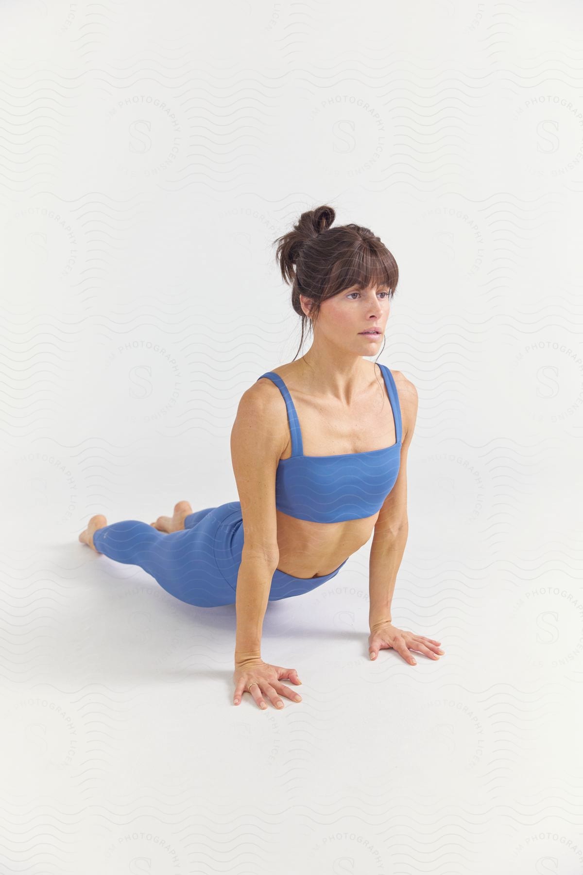 A woman practicing yoga wearing blue workout clothes.