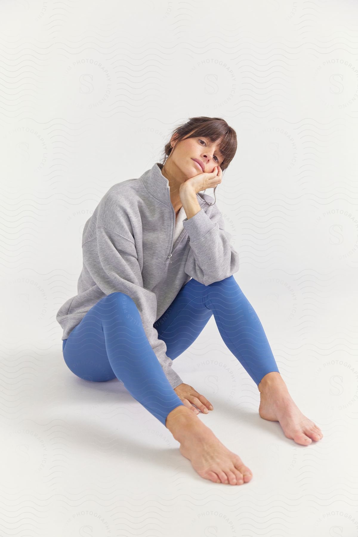 A woman models blue leggings and fleece activewear against a white backdrop