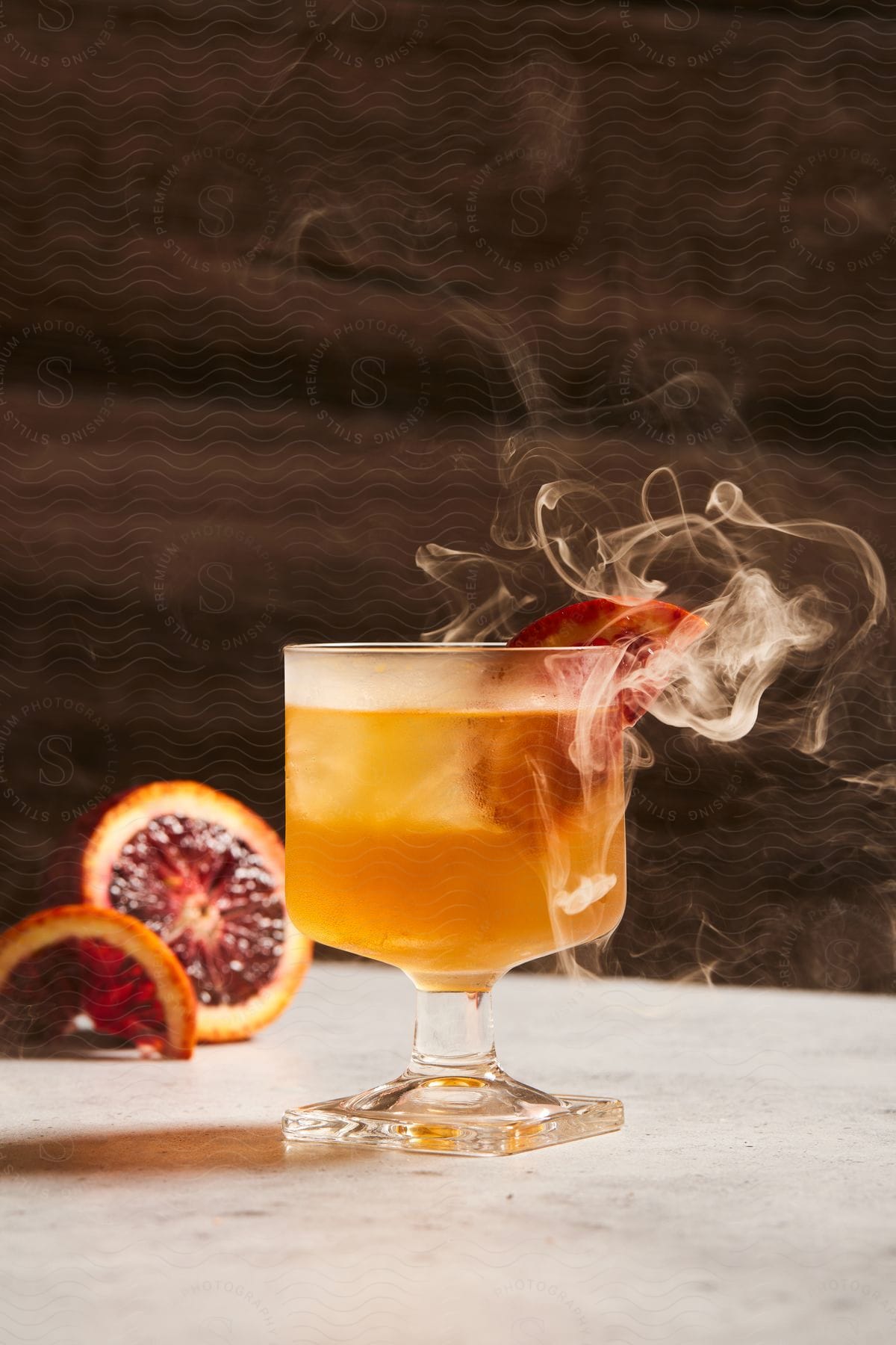 smoking orange beverage served in a cup with a slice of blood orange as garnish