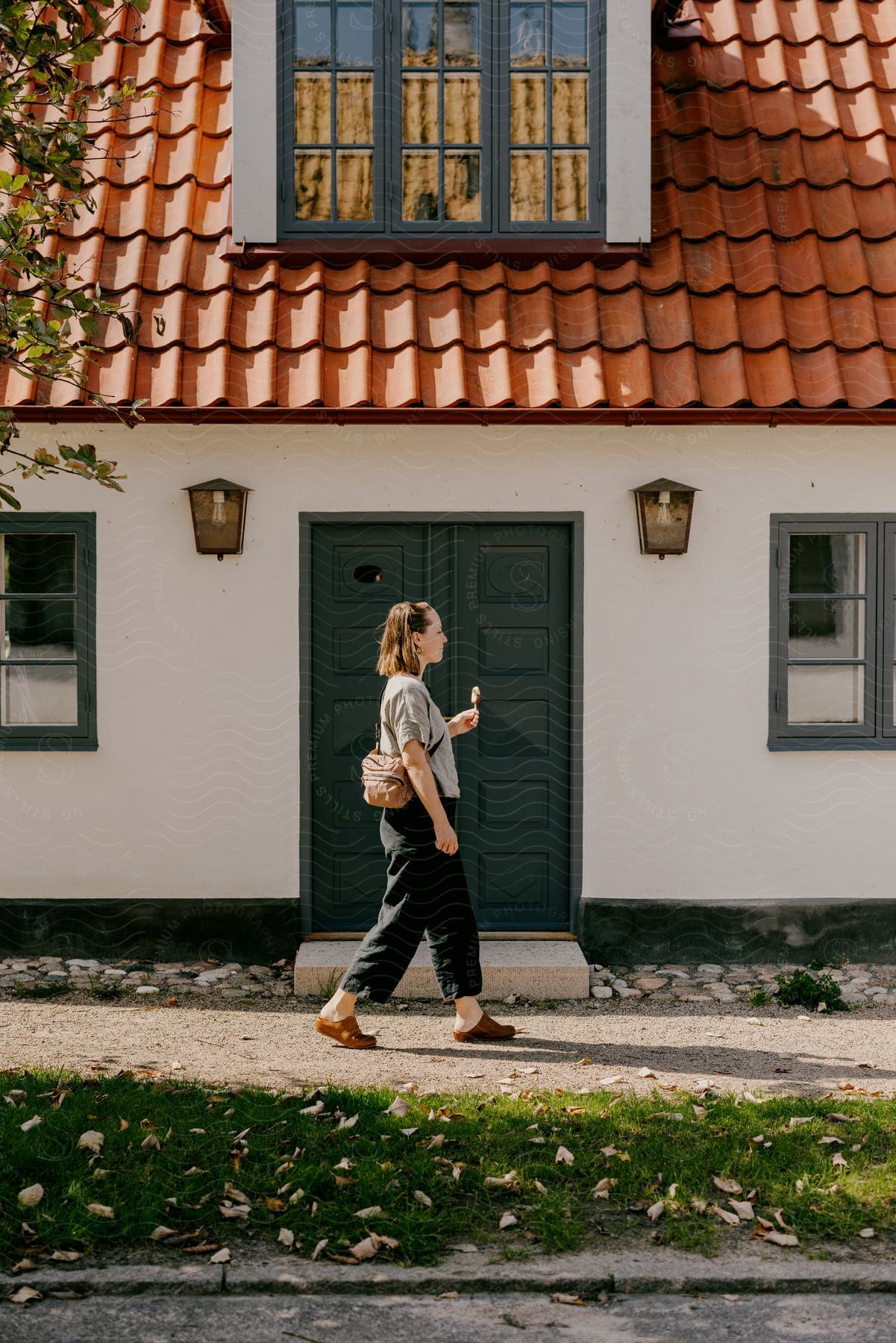 A lady is walking past the front door of a home.