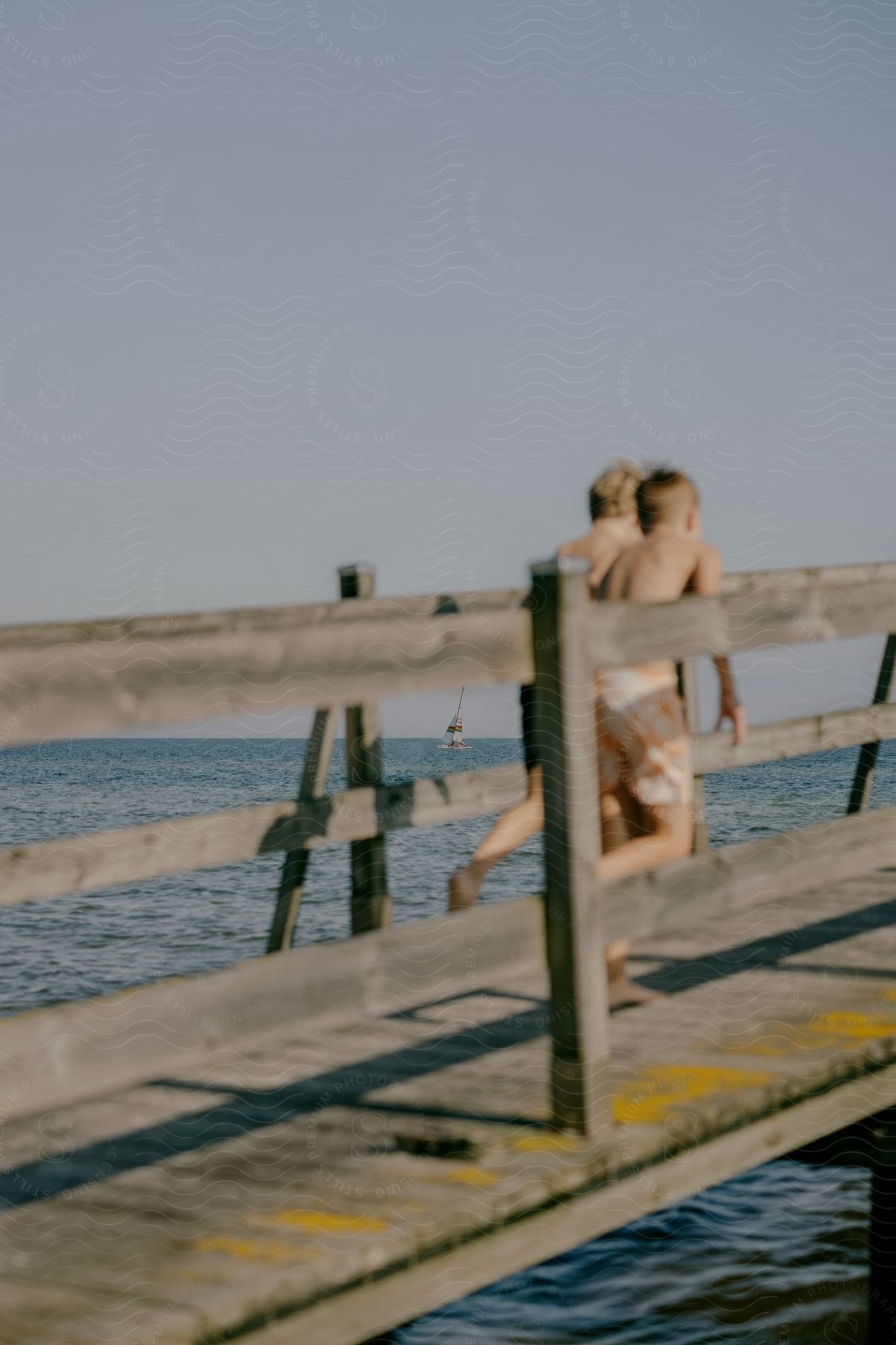 Two young boys running on an ocean pier on a bright sunny day