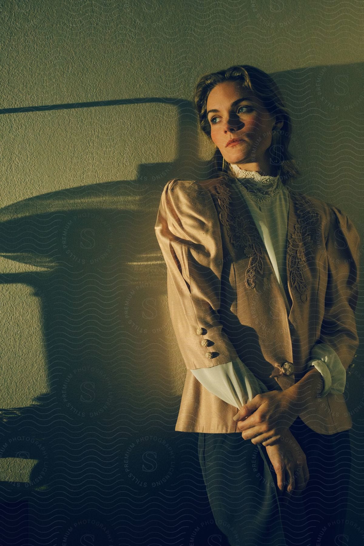 A woman leaning against the wall, posing in a classic blouse.