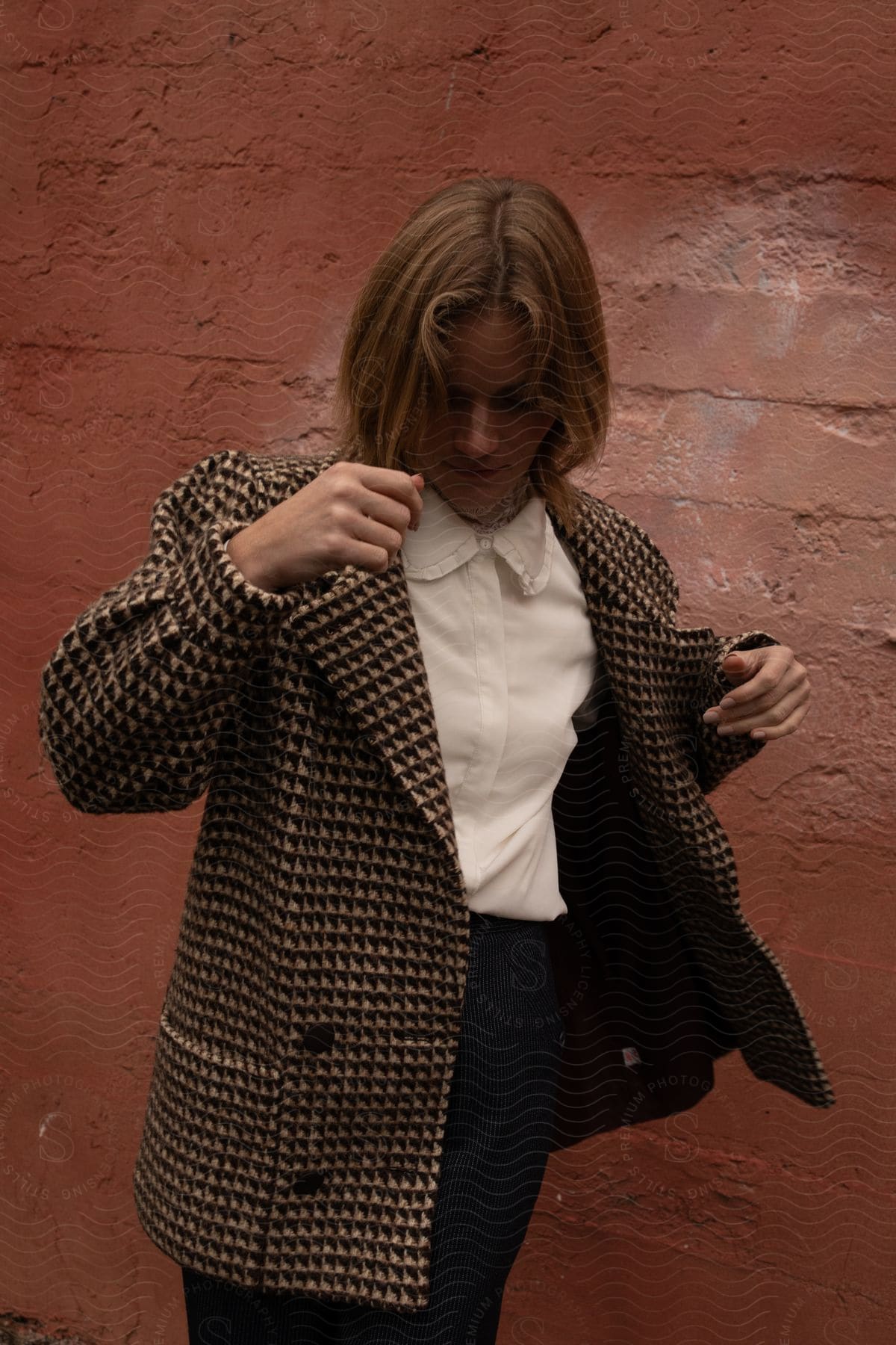 Woman posing against a red wall wearing a blazer.