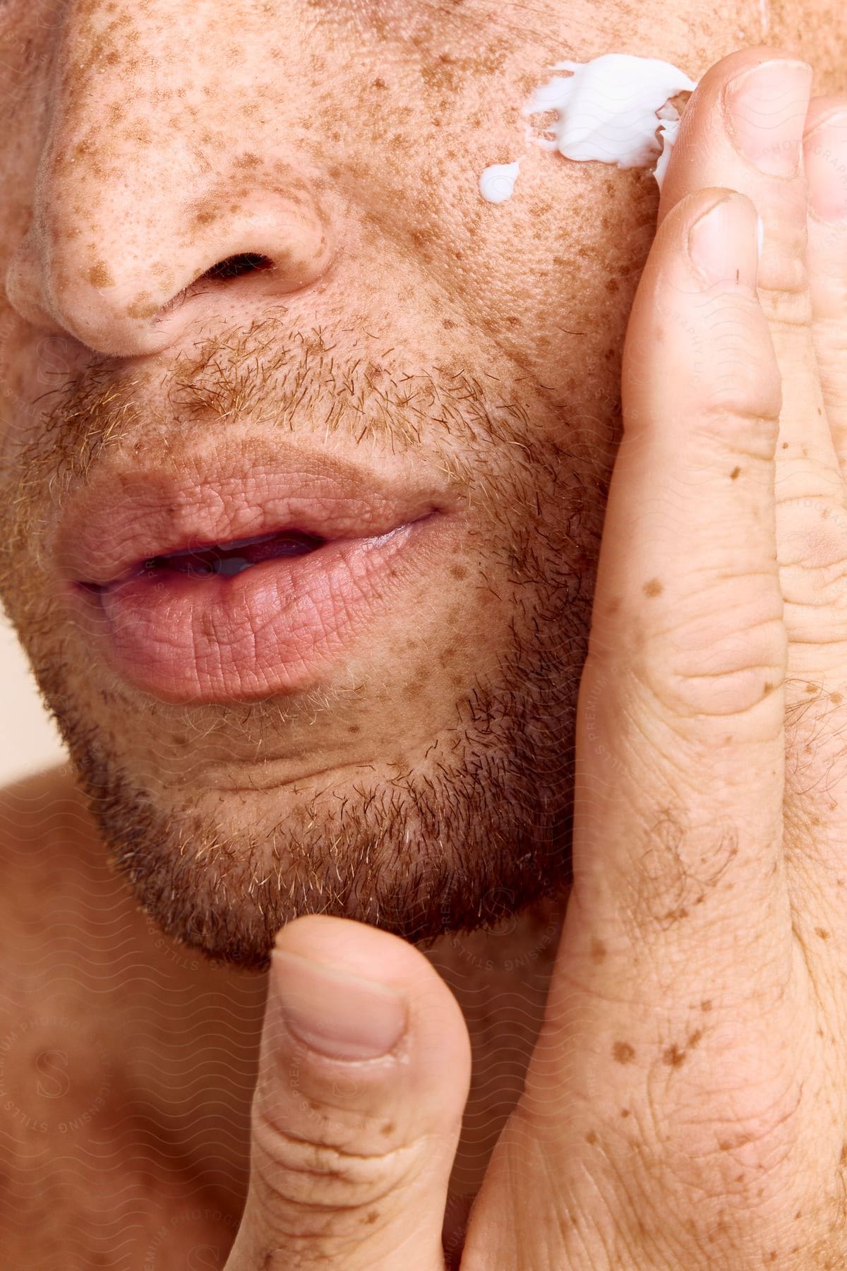 A man is applying a white cream to his face.