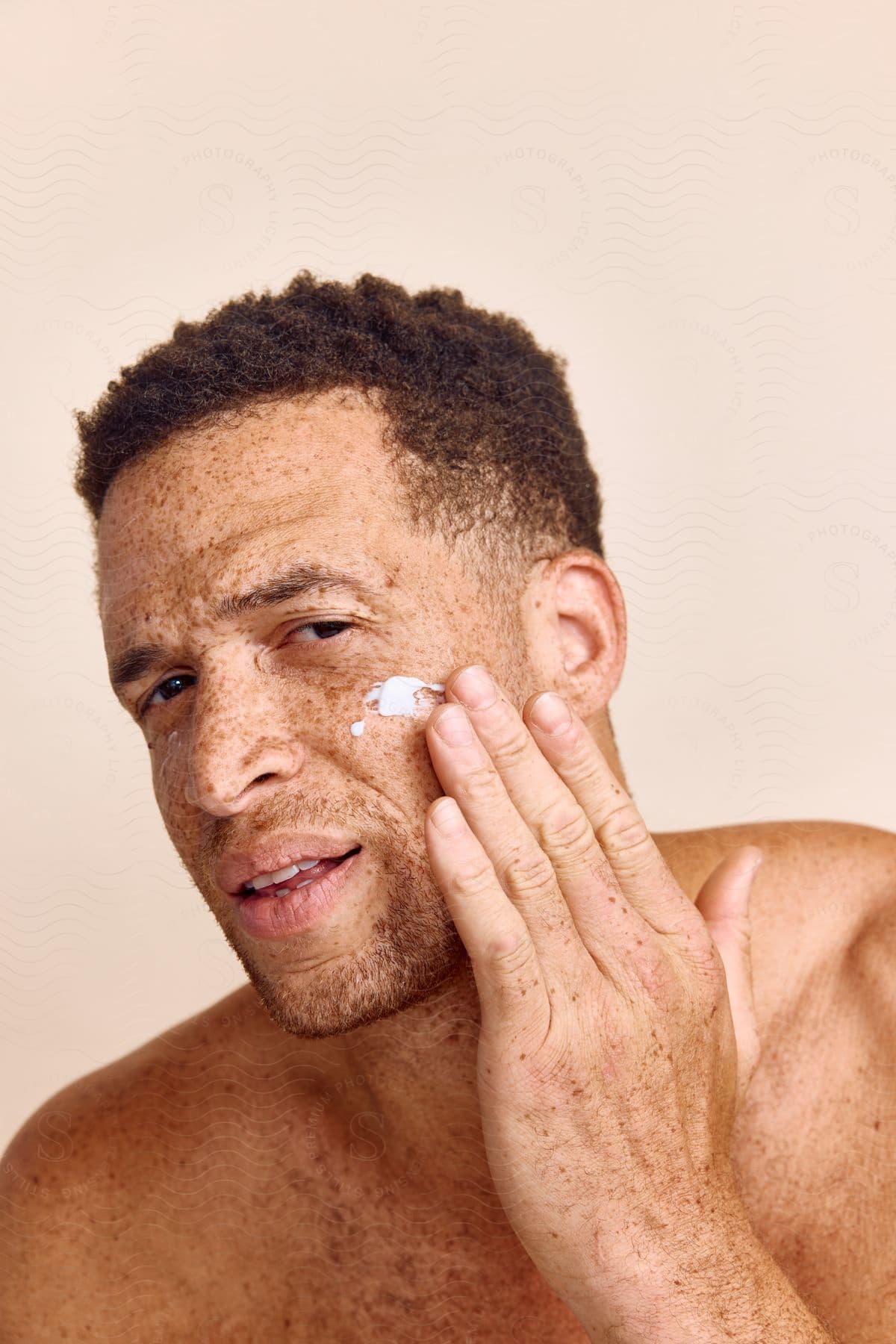 a man applies lotion to his cheek