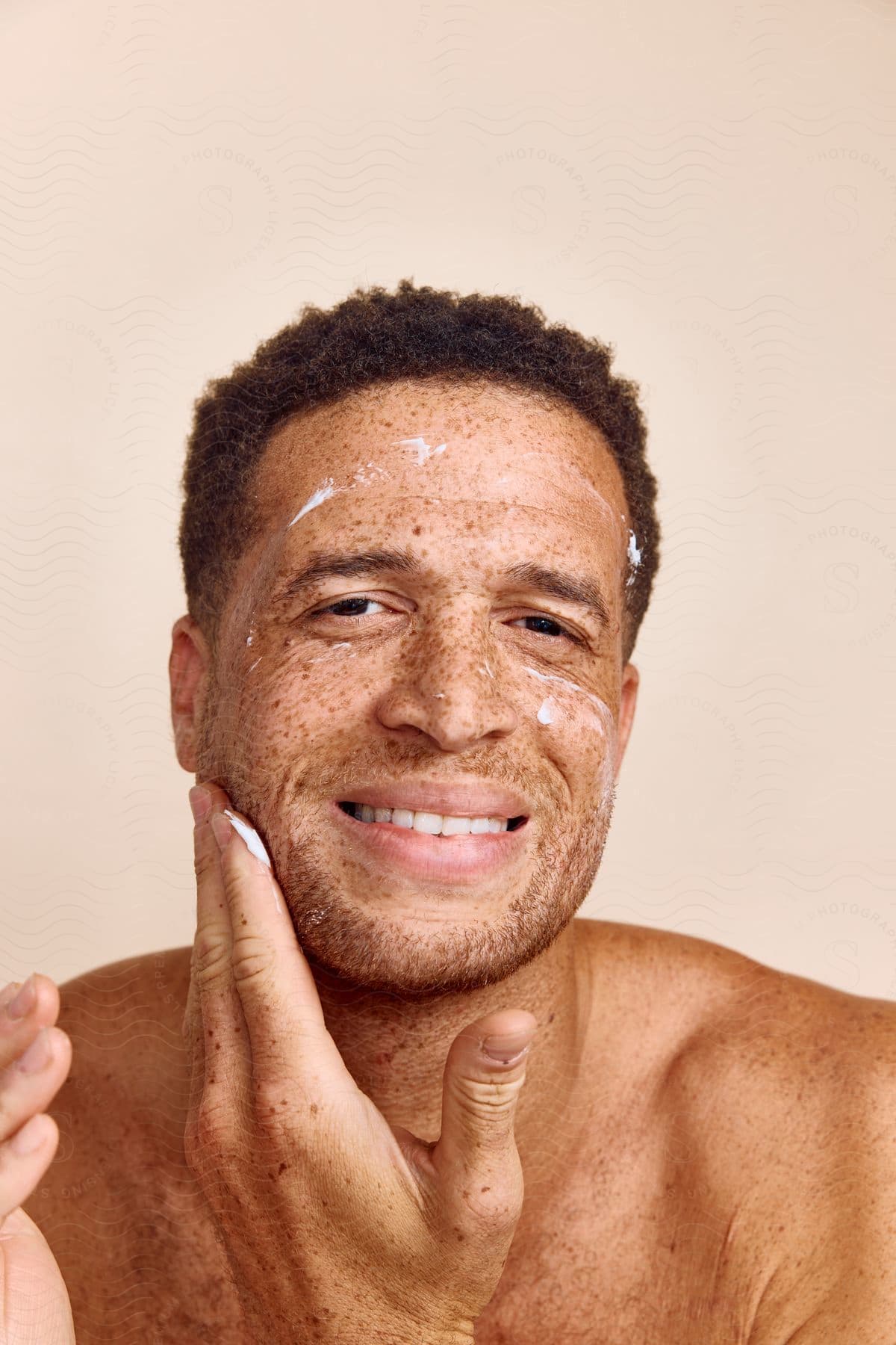 Smiling man applies lotion to face