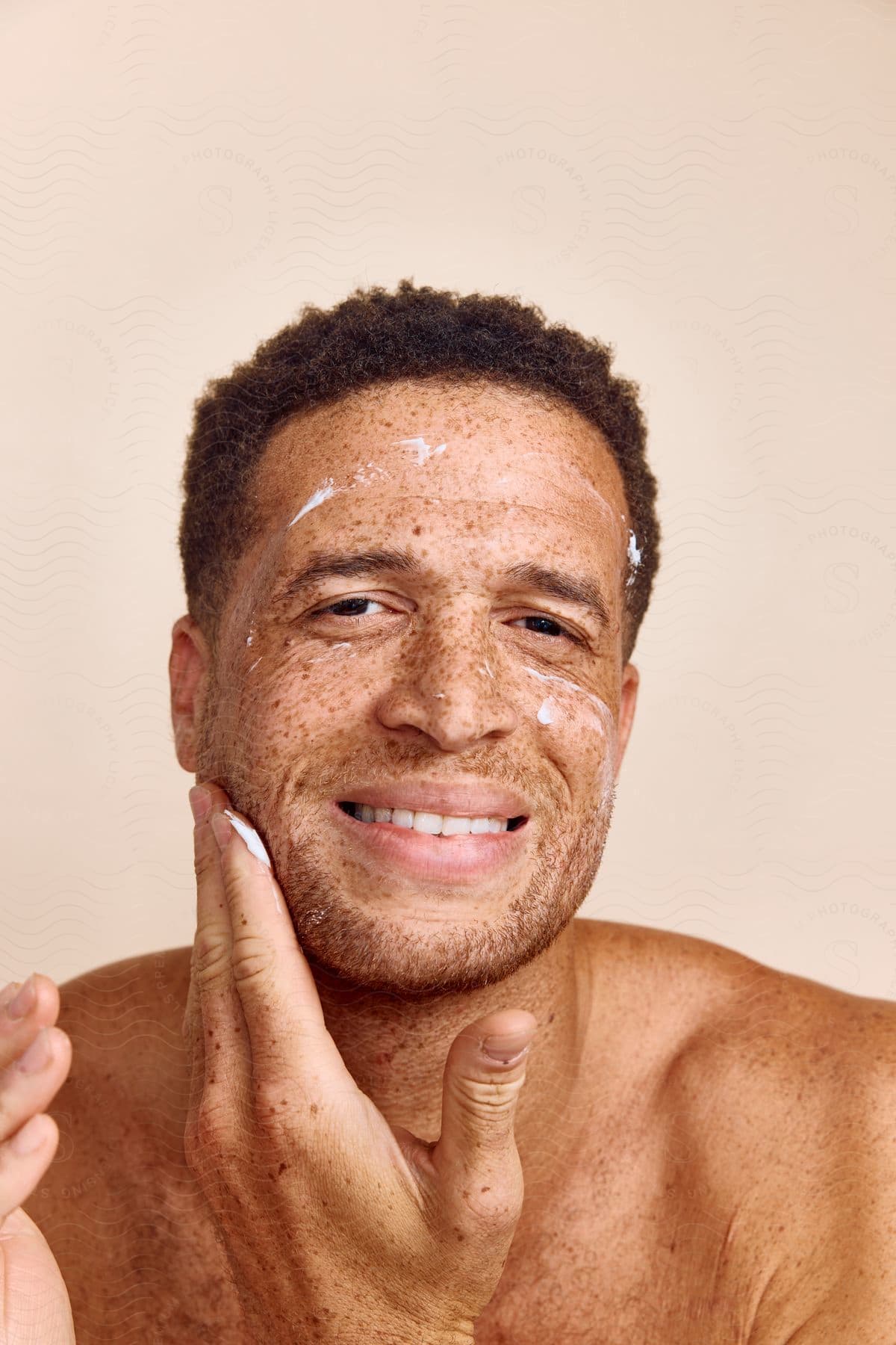 Smiling Man Applies Lotion To Face