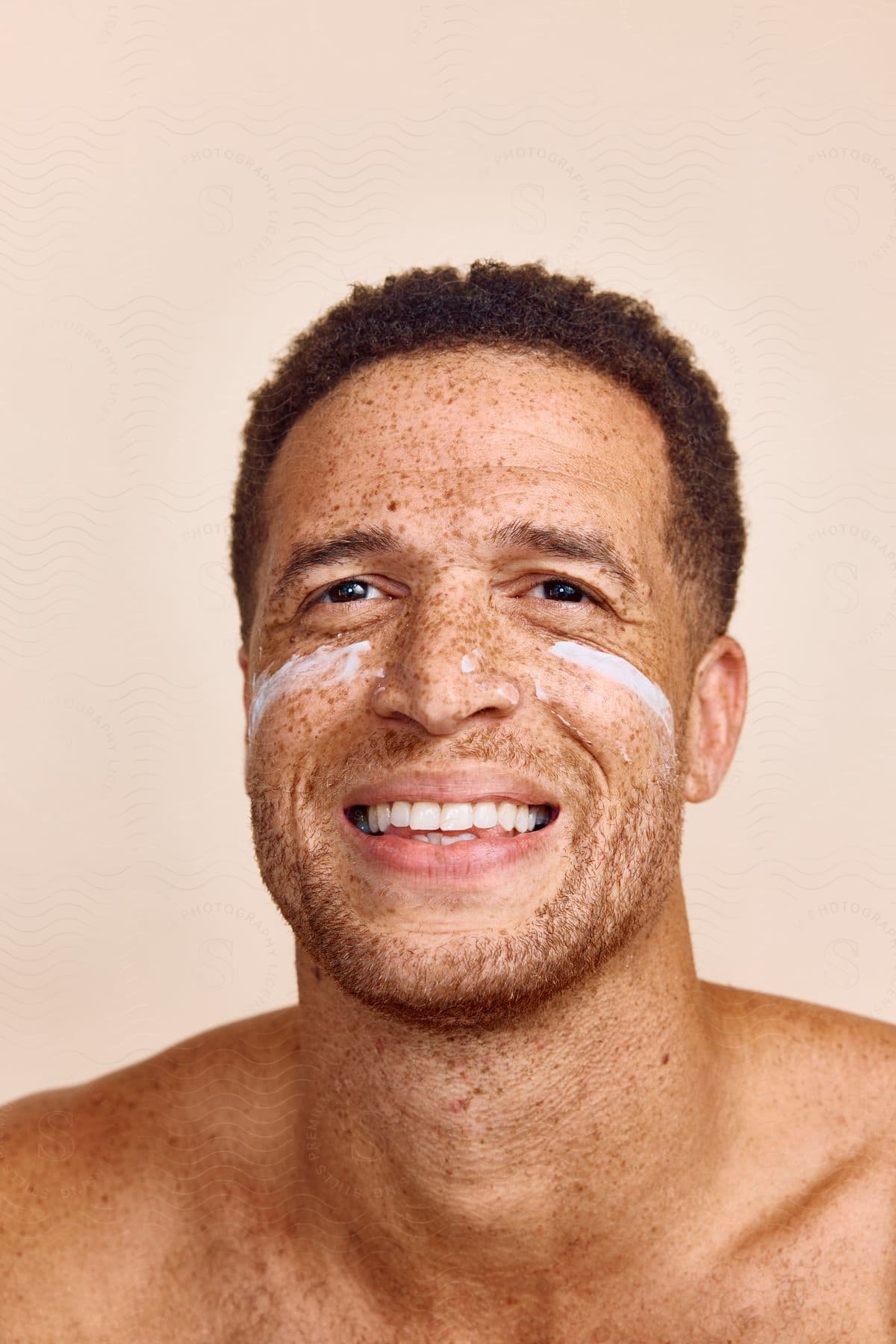 close-up of a smiling man's face wearing sunscreen cream indoors