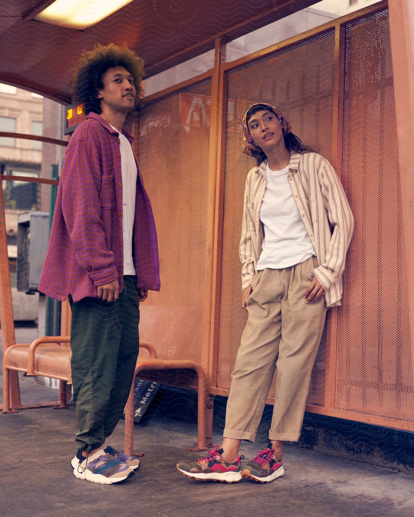 A man and woman standing in a room together modeling clothing