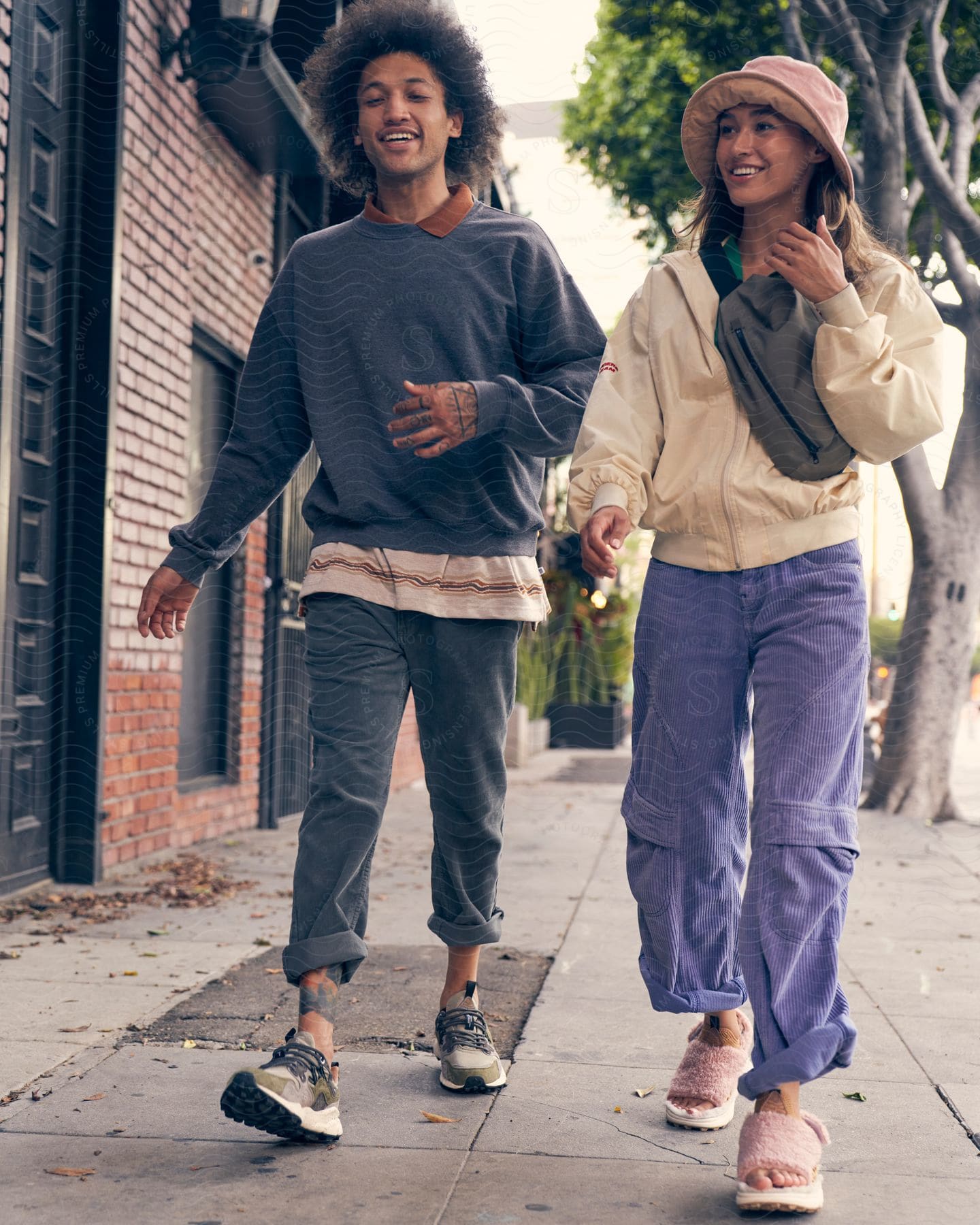 A man and woman in streetwear walking down a city street.