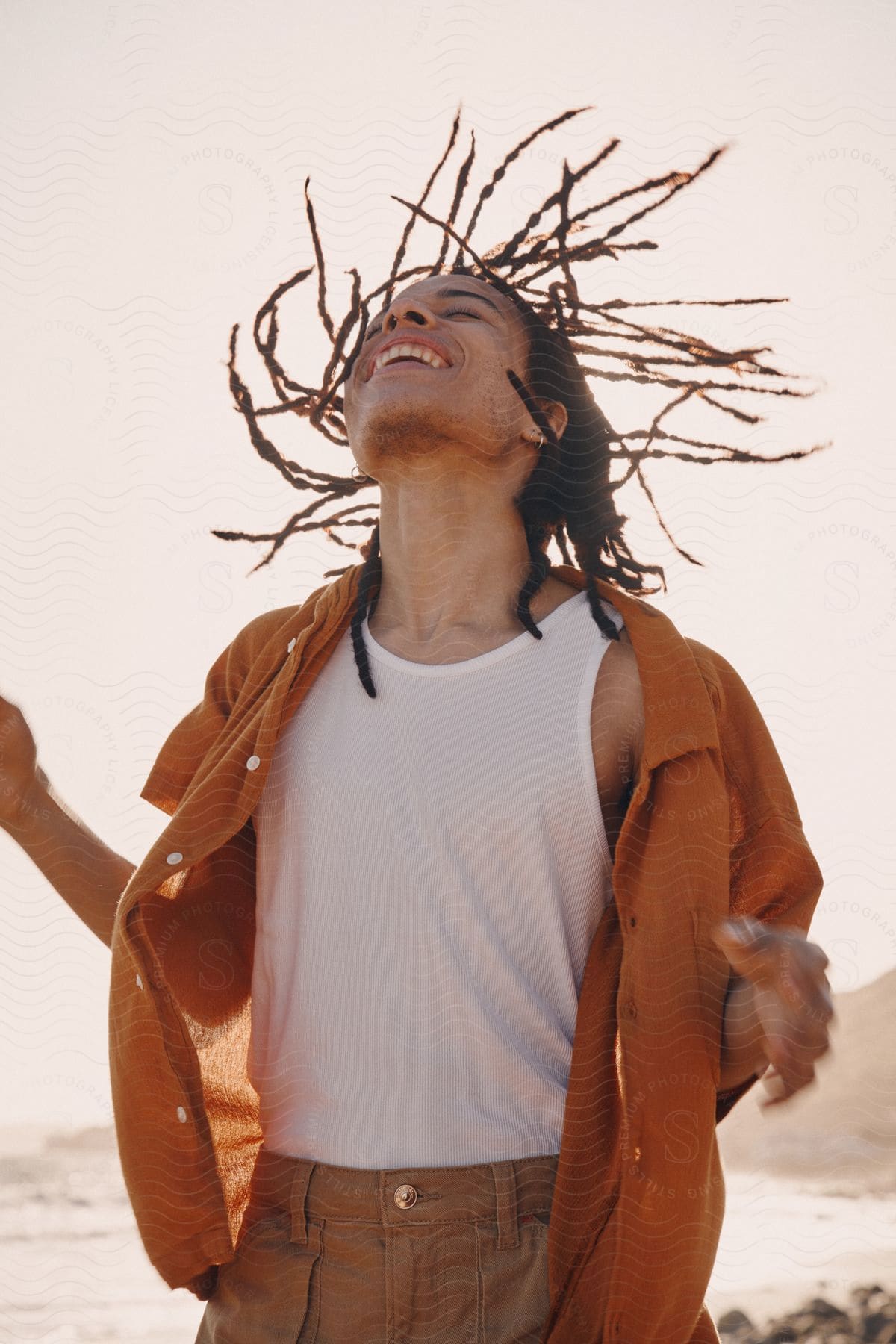 Young man looking with closed eyes upwards and smiling on the beach.