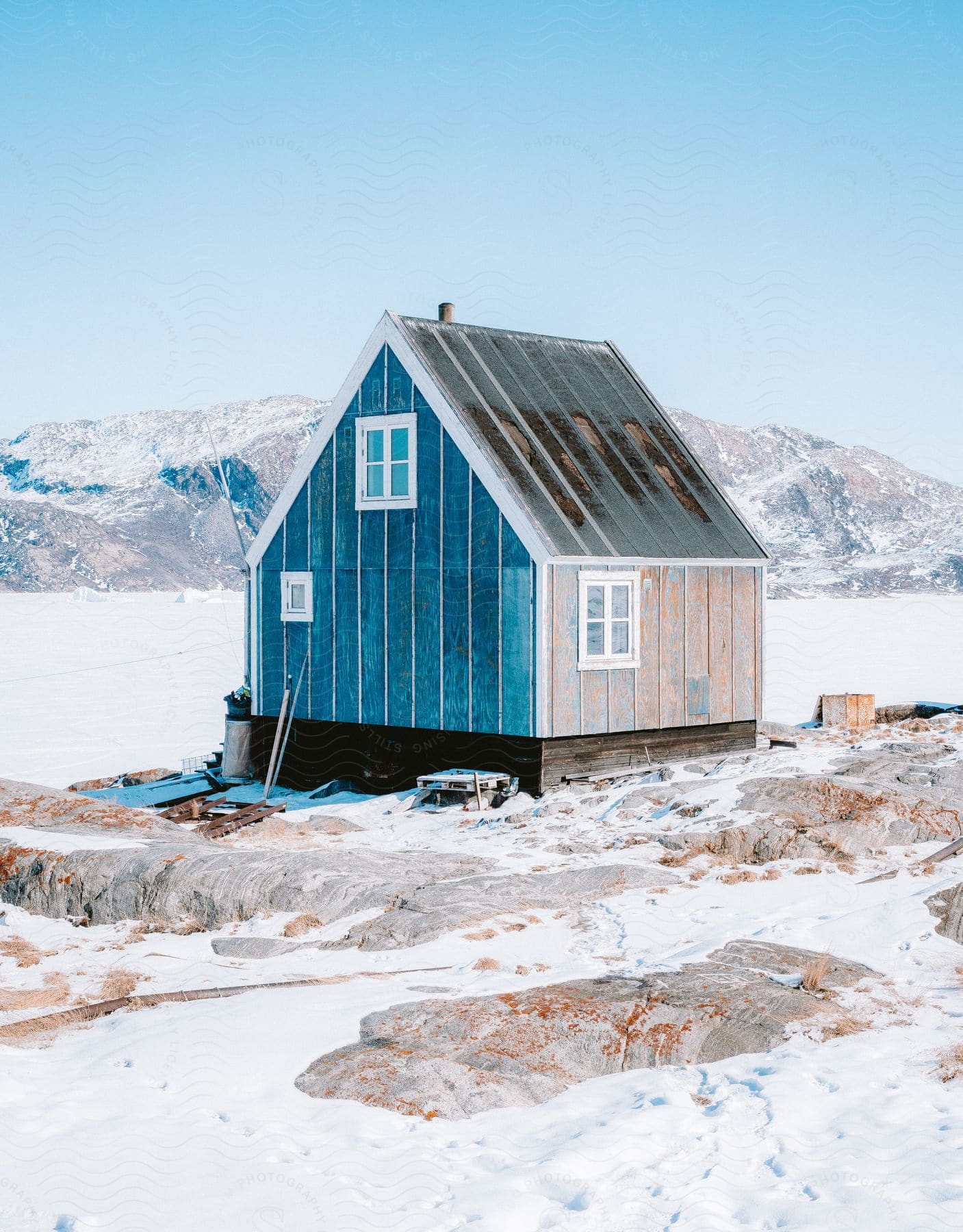 a small hut in the wilderness surrounded by mountain with the environment covered in snow