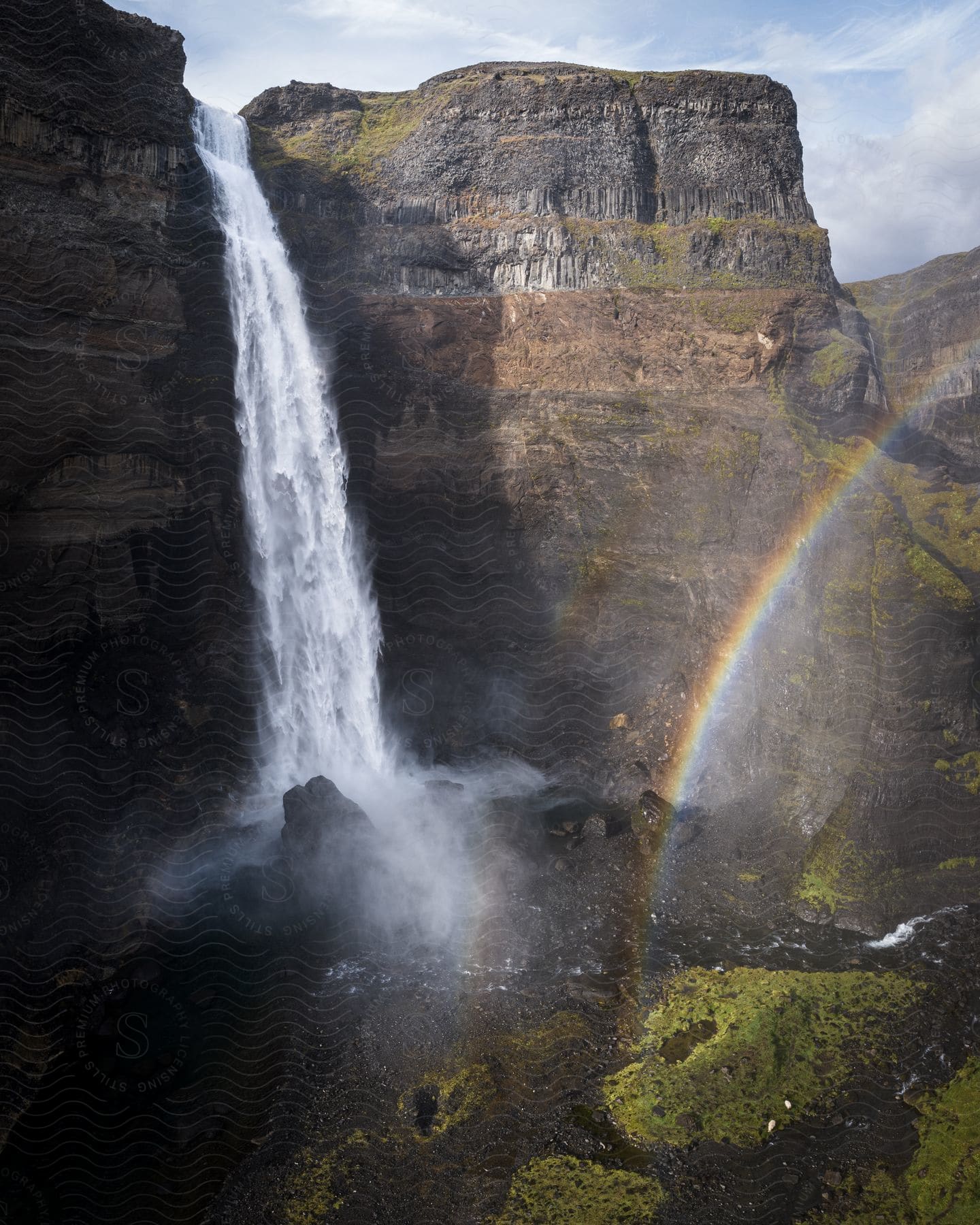 Rainbow gleams over river at the base of the Haifoss waterfall.