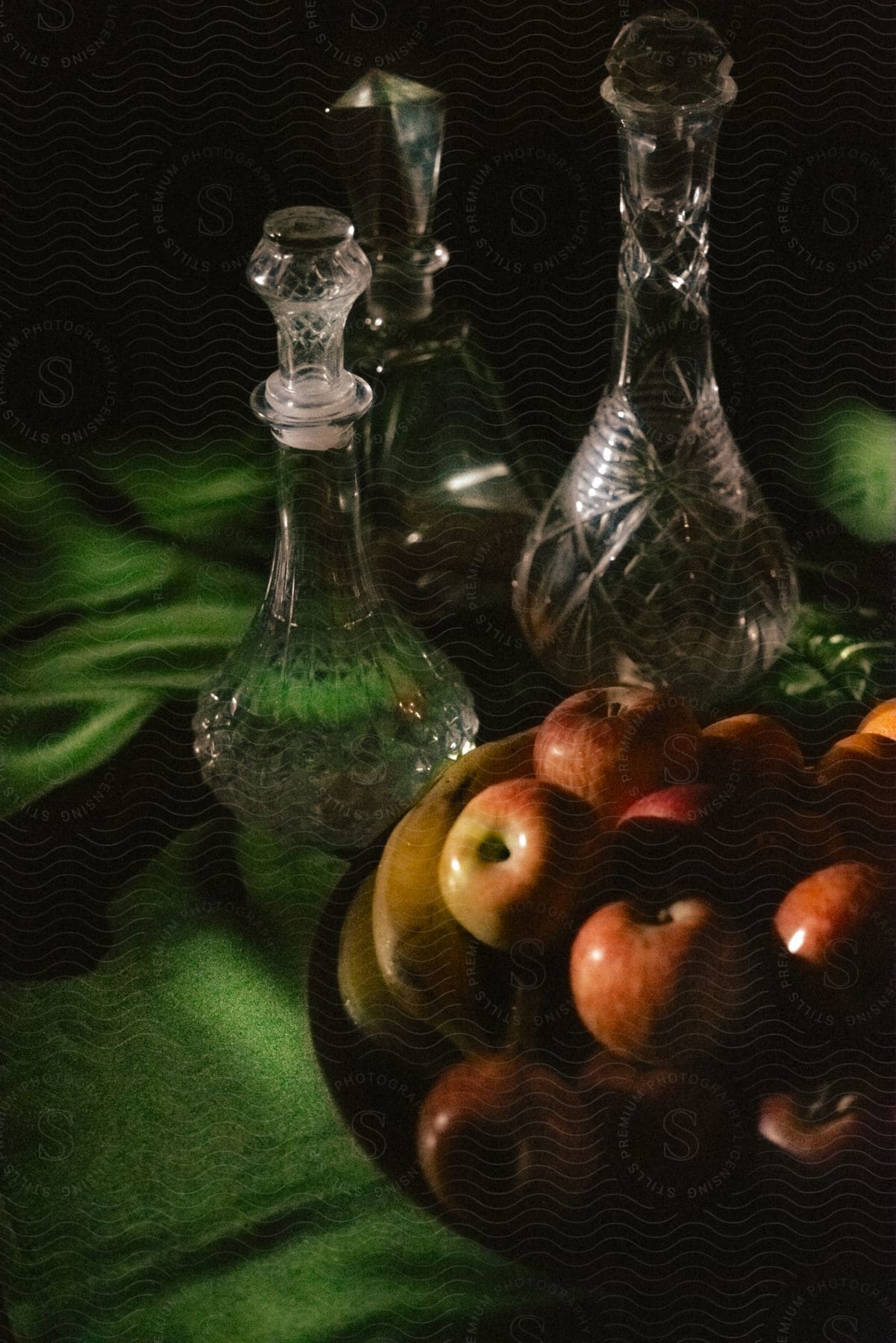 A bowl of fruit and three decorated glass bottles.