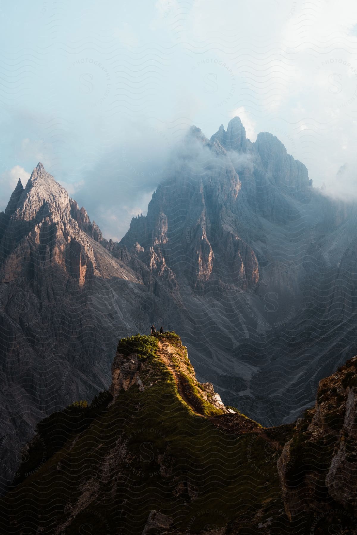 Aerial view of tall mountains in the distance with clouds above them.