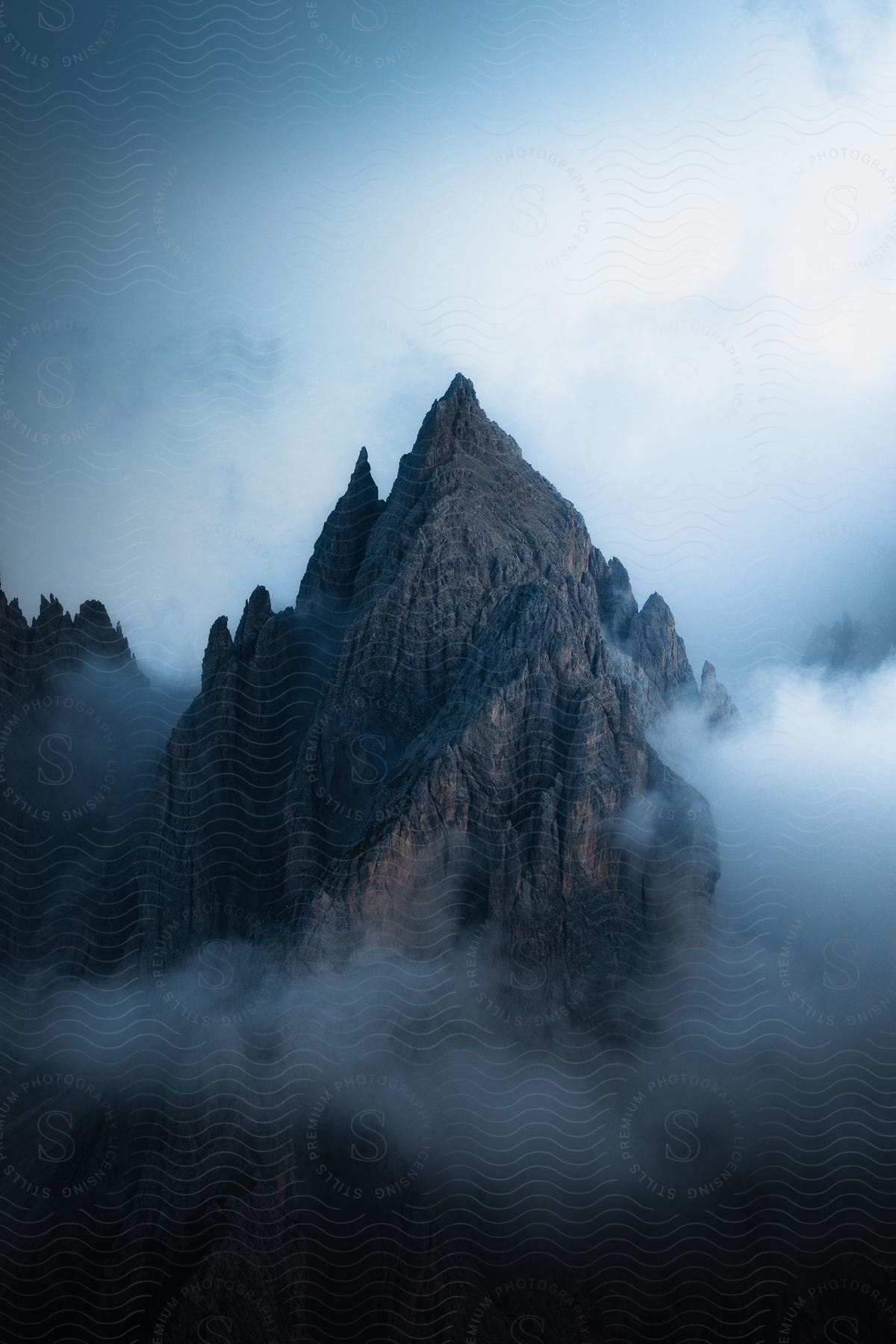 Peaks of craggy mountains show through low lying clouds.