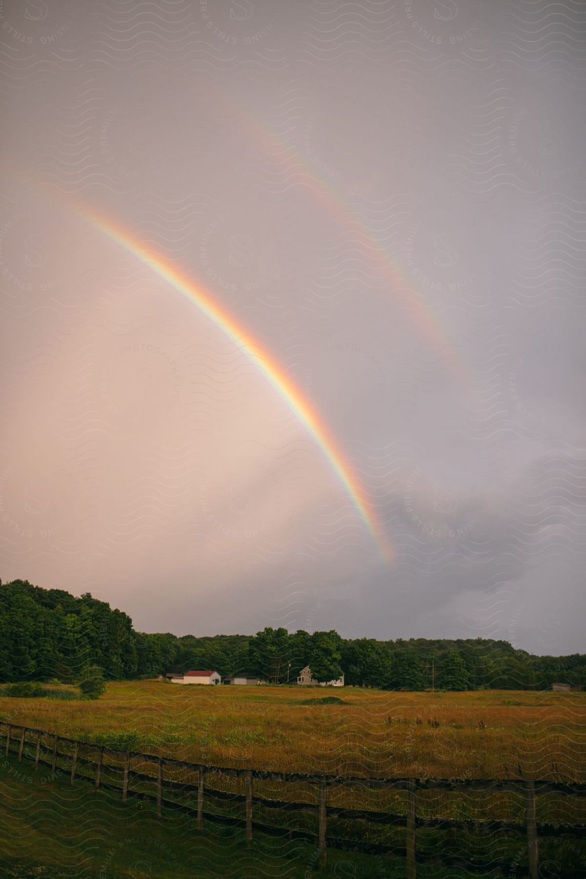 A double rainbow arcing over a small farm.