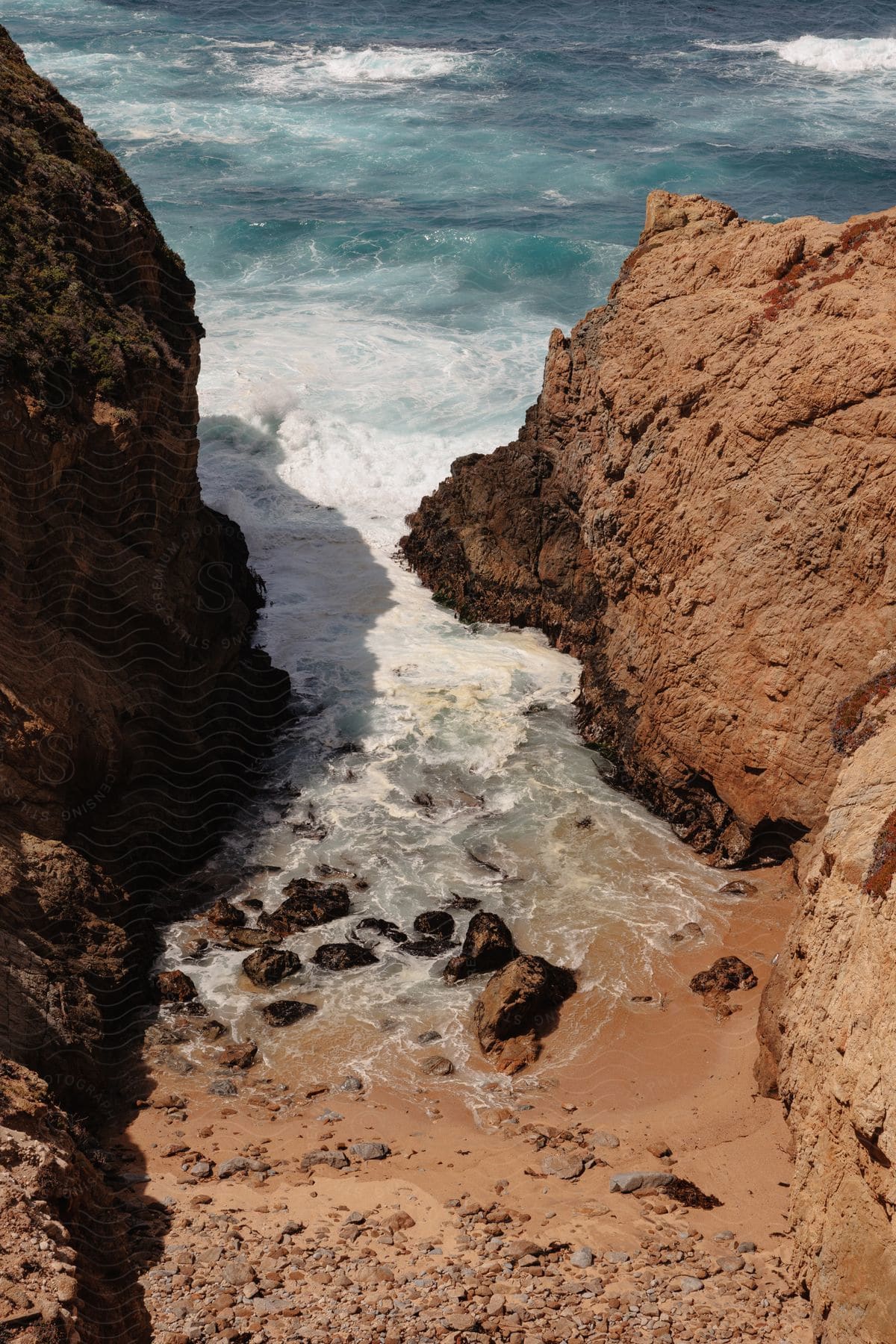 Waves roll into shore as water splashes over rocks in the cove along the promontory