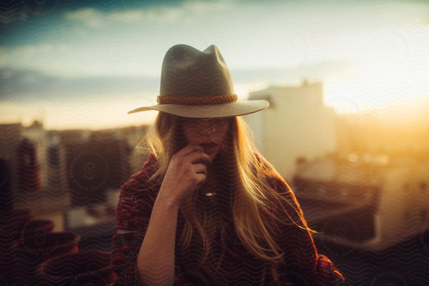 A young woman with long, blonde hair wears a cowboy hat at sunrise.