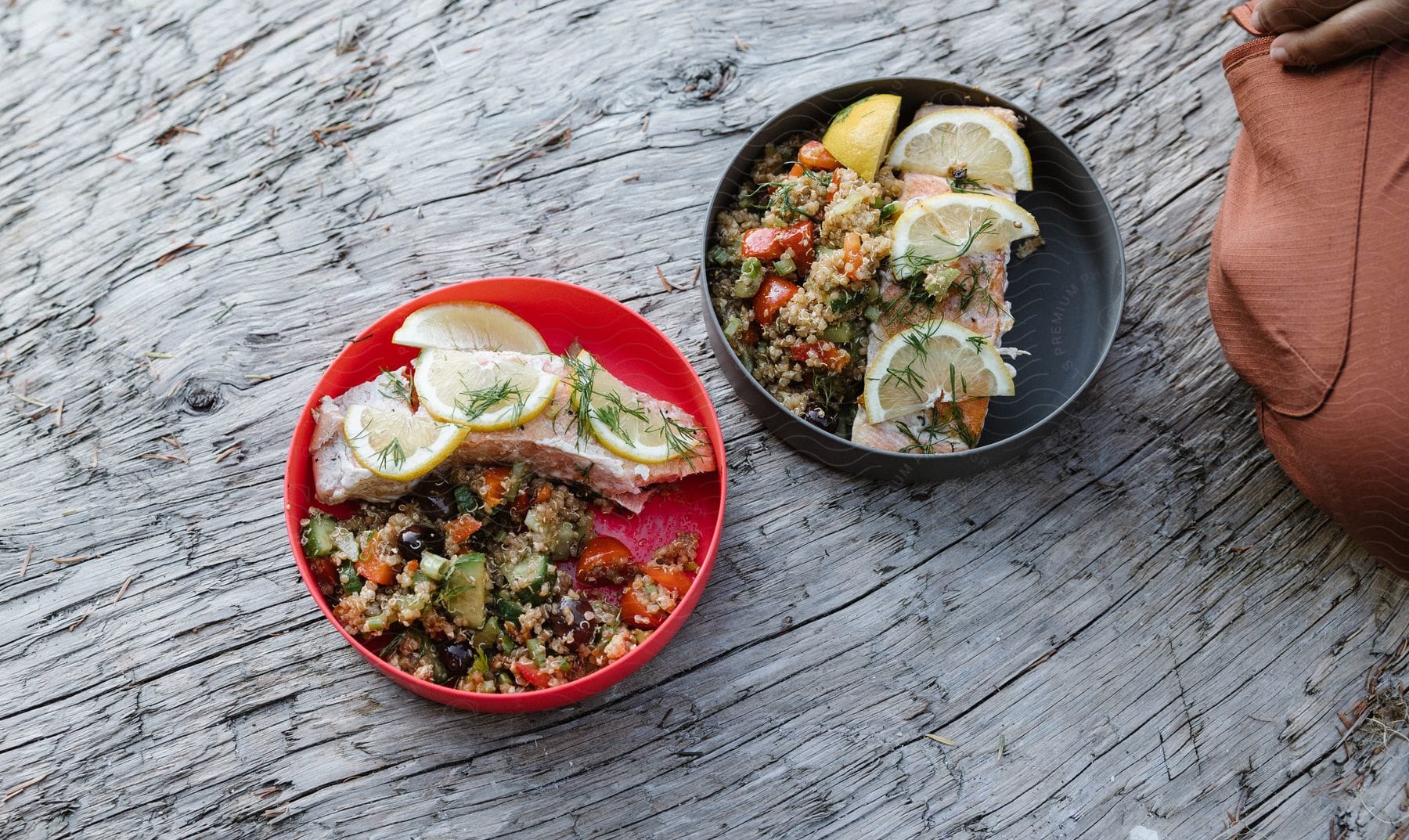 Bowls with fish and grain recipe sit on old wooden surface.