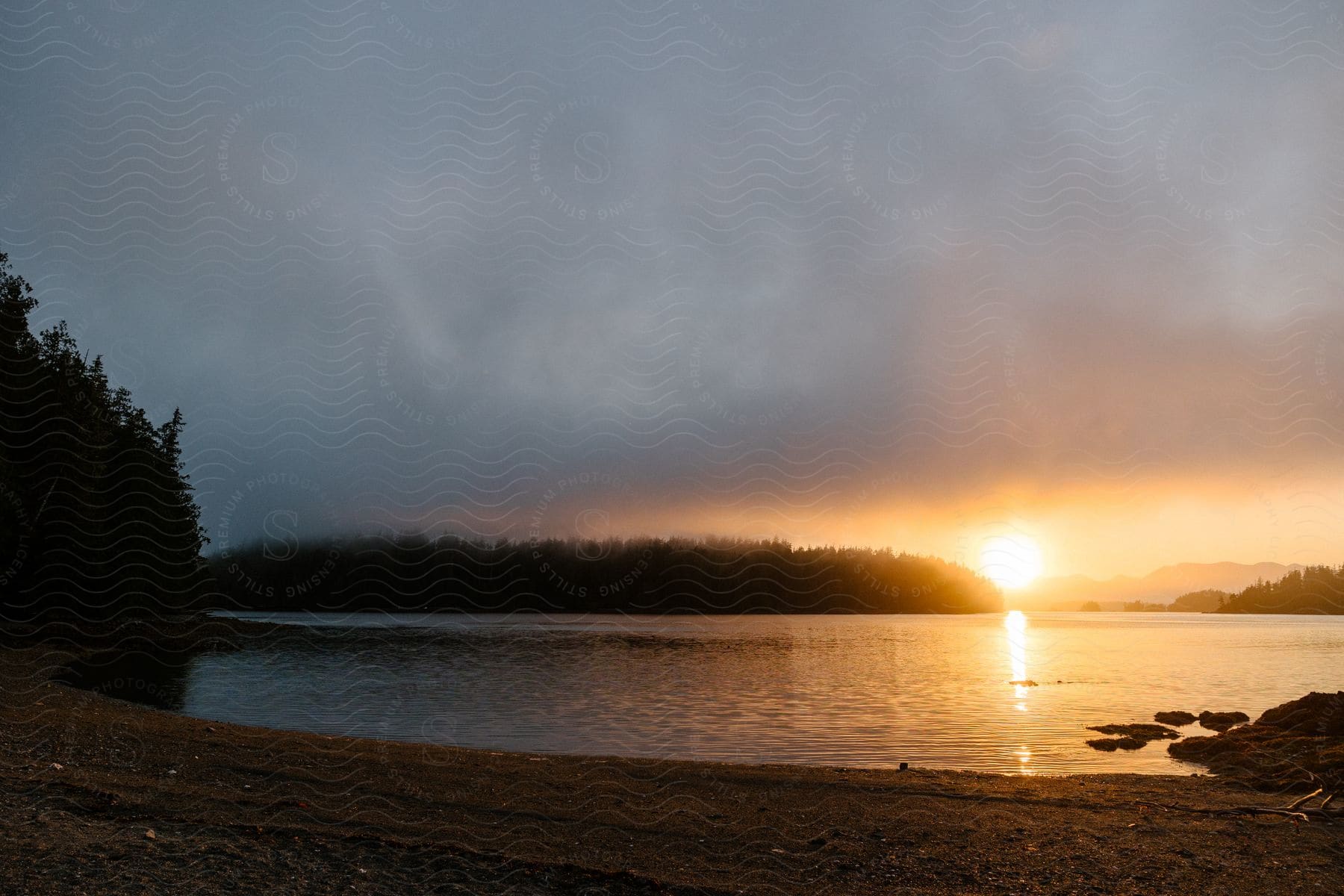 A view of a calm river, surrounded by vegetation, with the sunrise on the horizon.