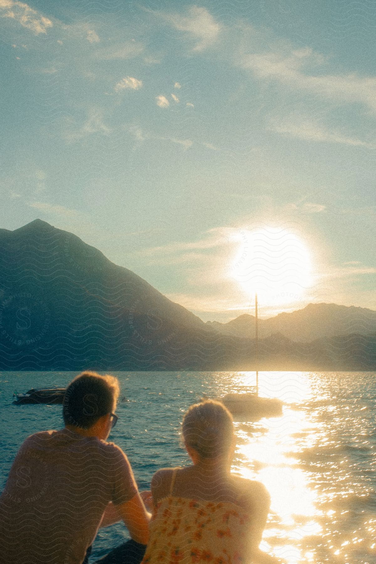 a man and woman watch boats sail through a lake