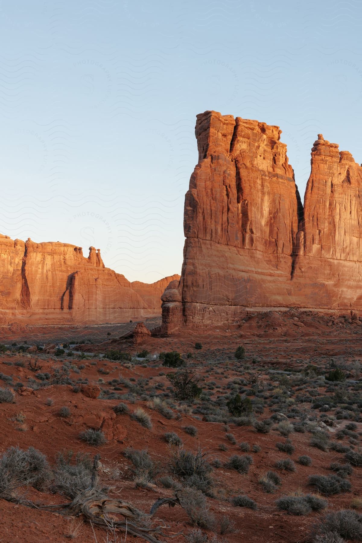 Stock photo of narrow rock formation faces cliff in desert on sunny day.