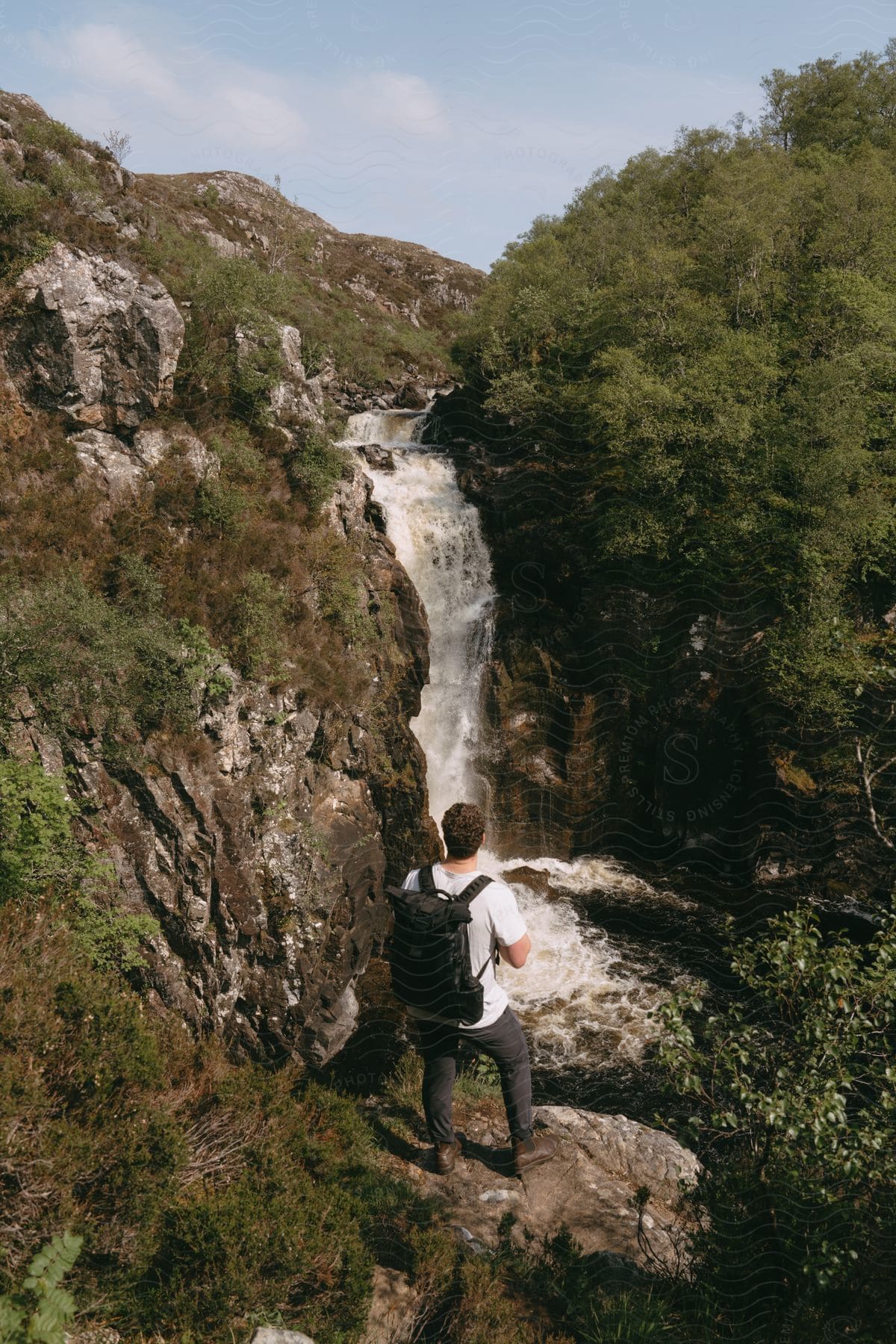 A man with a backpack looking at the waterfall during the day