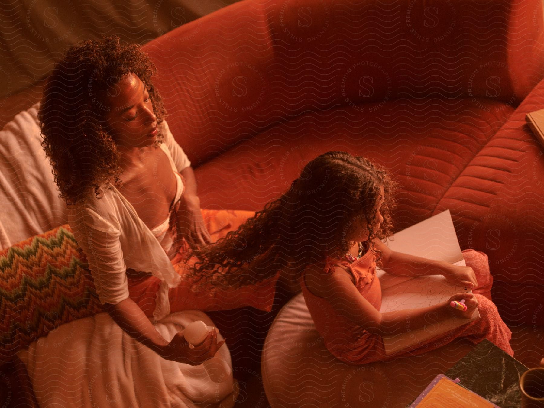 mother with curly hair does daughter's hair in the living room