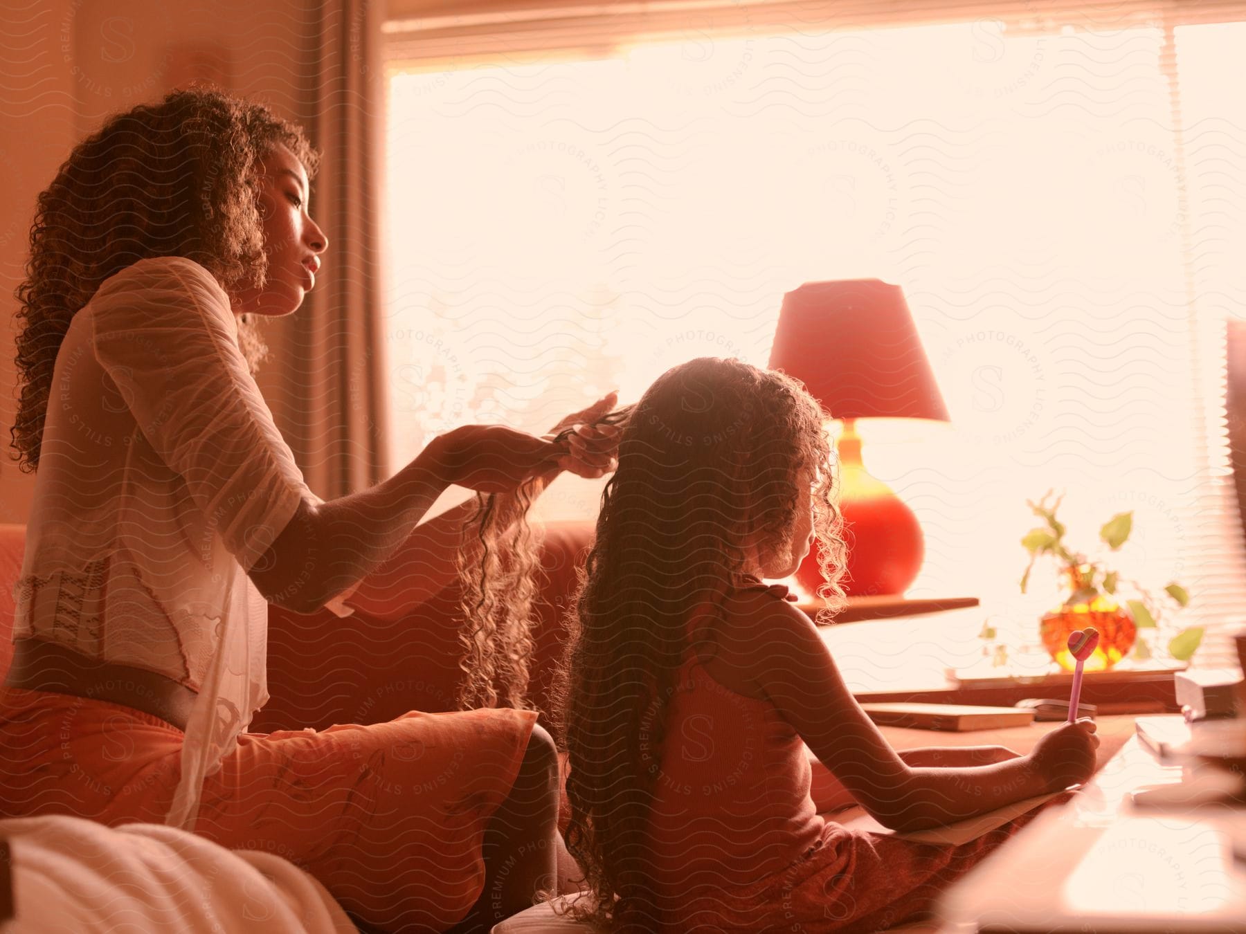 a woman braids her daughter's long hair