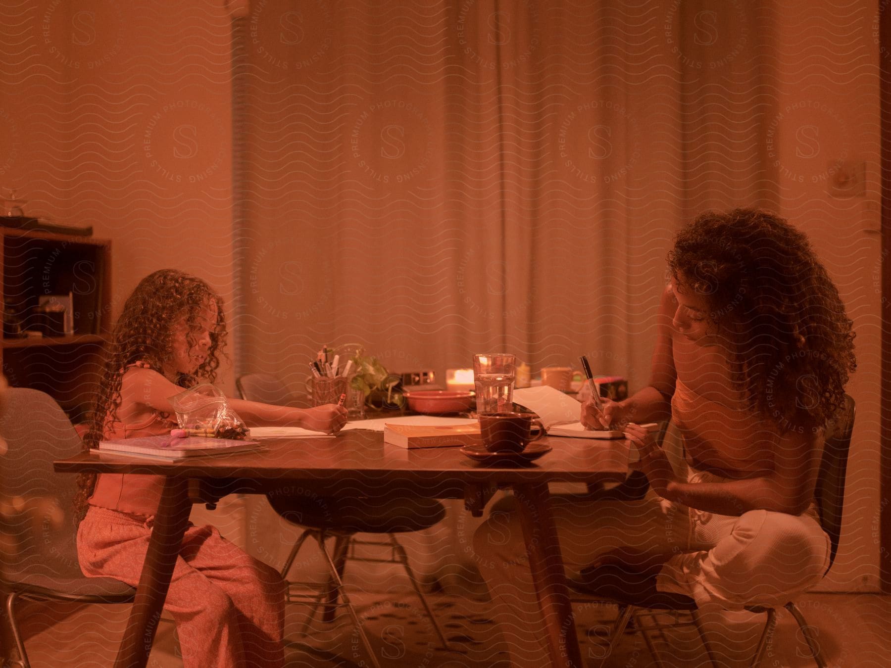 Mother and daughter drawing and writing at a table at home.