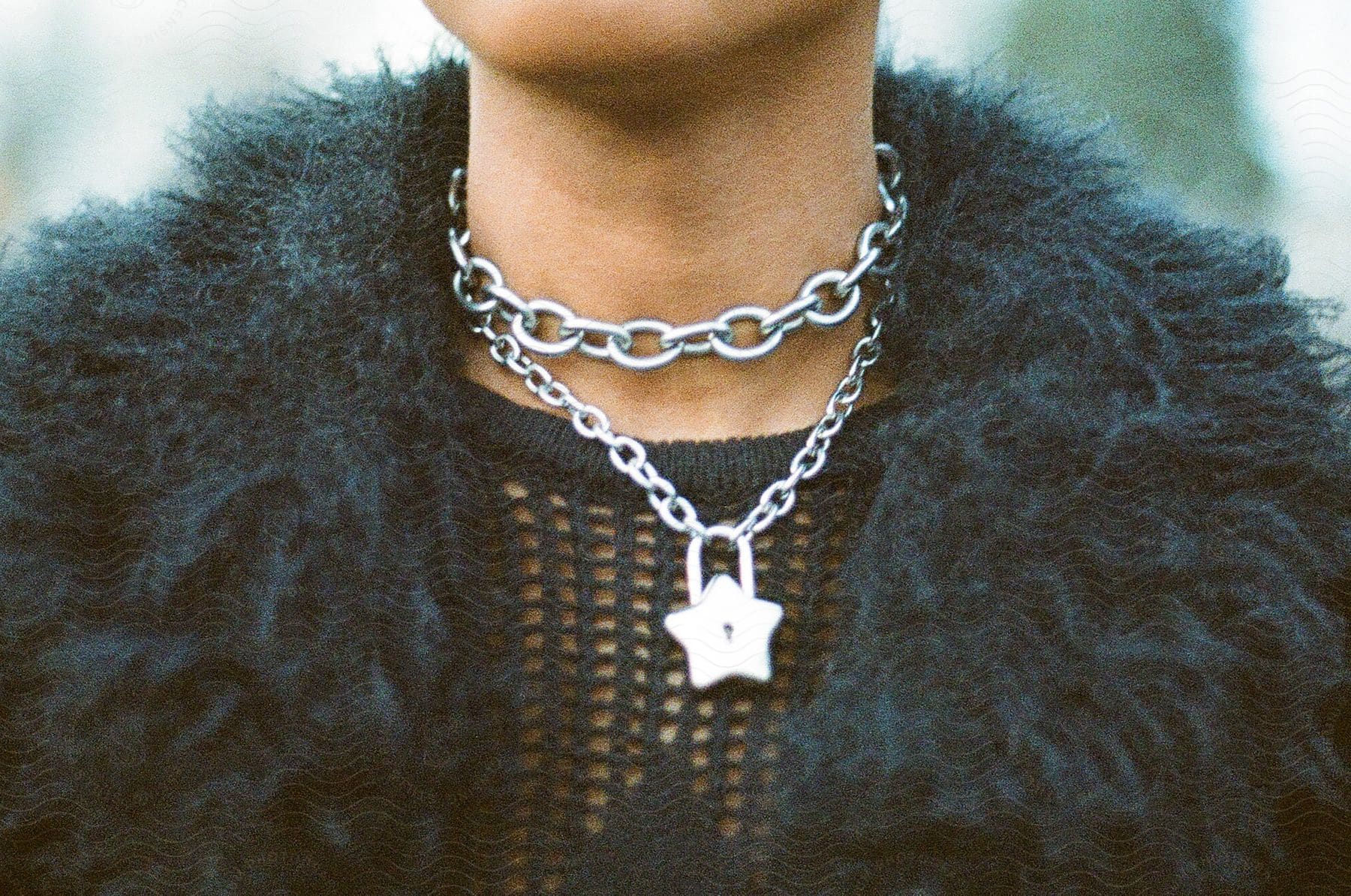 Close up of woman’s neck wearing Star Lock Pendant Necklace and black waistcoat