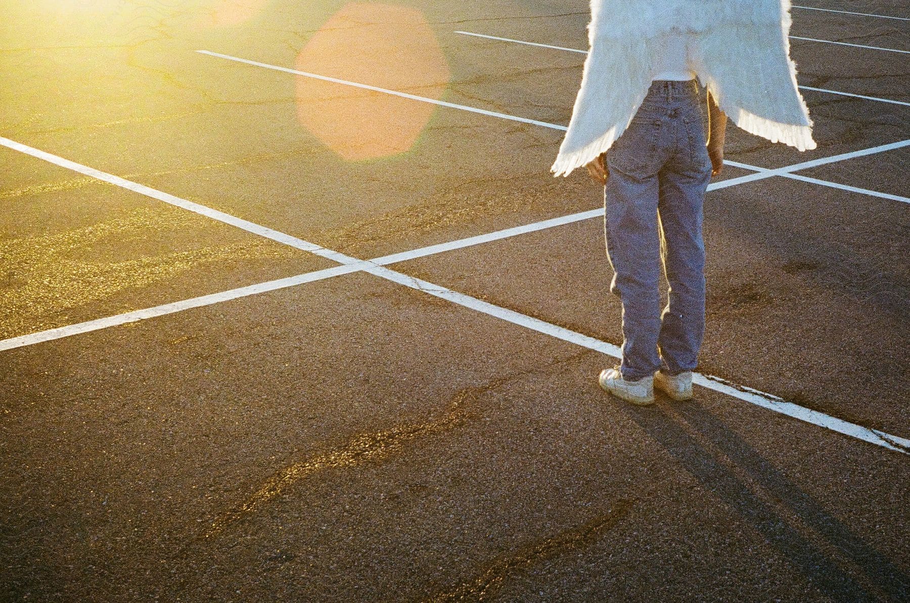 a woman stands in a parking lot wearing angel wings