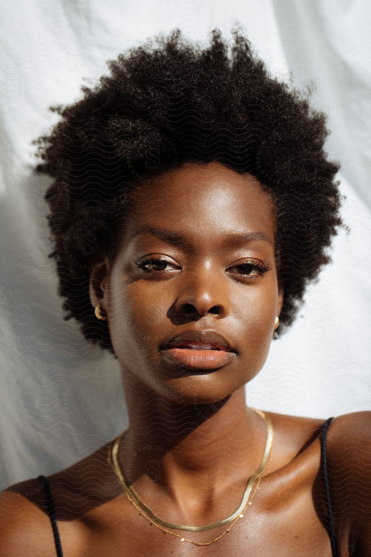 A black woman with a short hairstyle wears golden jewelry.