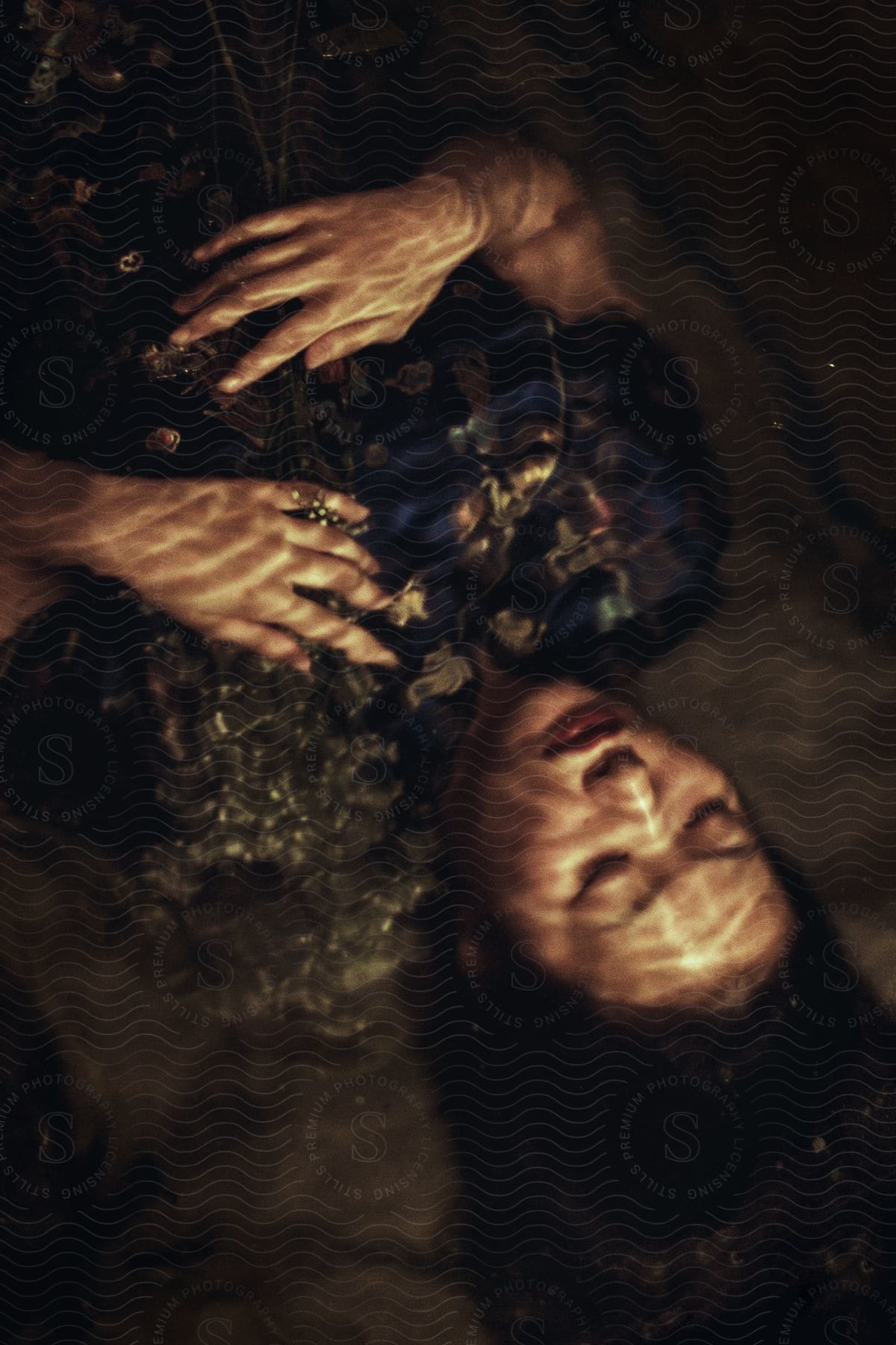 Light and shadow cover a woman lying on the floor with her eyes closed and her hands on her chest