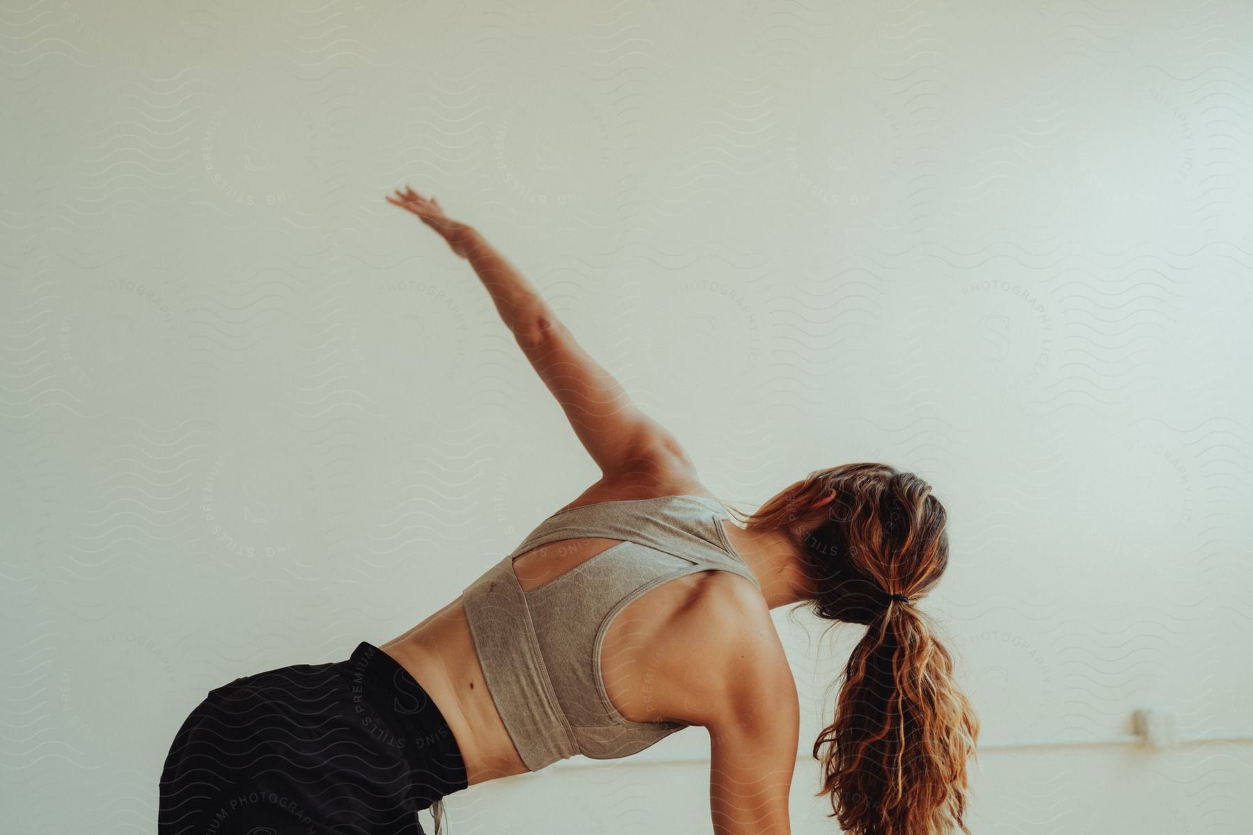 A woman on her hands and knees holds her arm upward as she performs a yoga pose