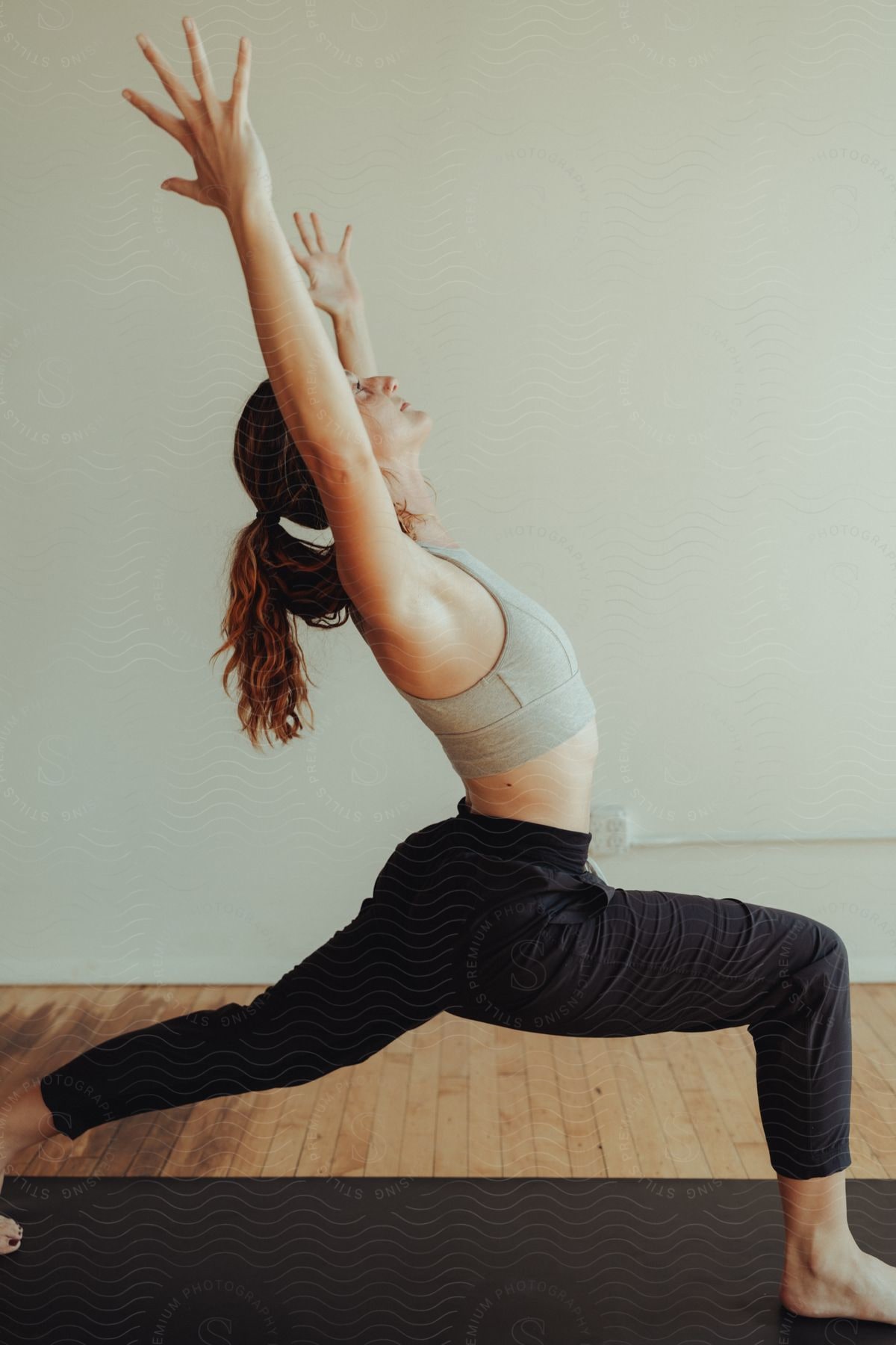 a young lady is doing yoga with her hands stretched upward