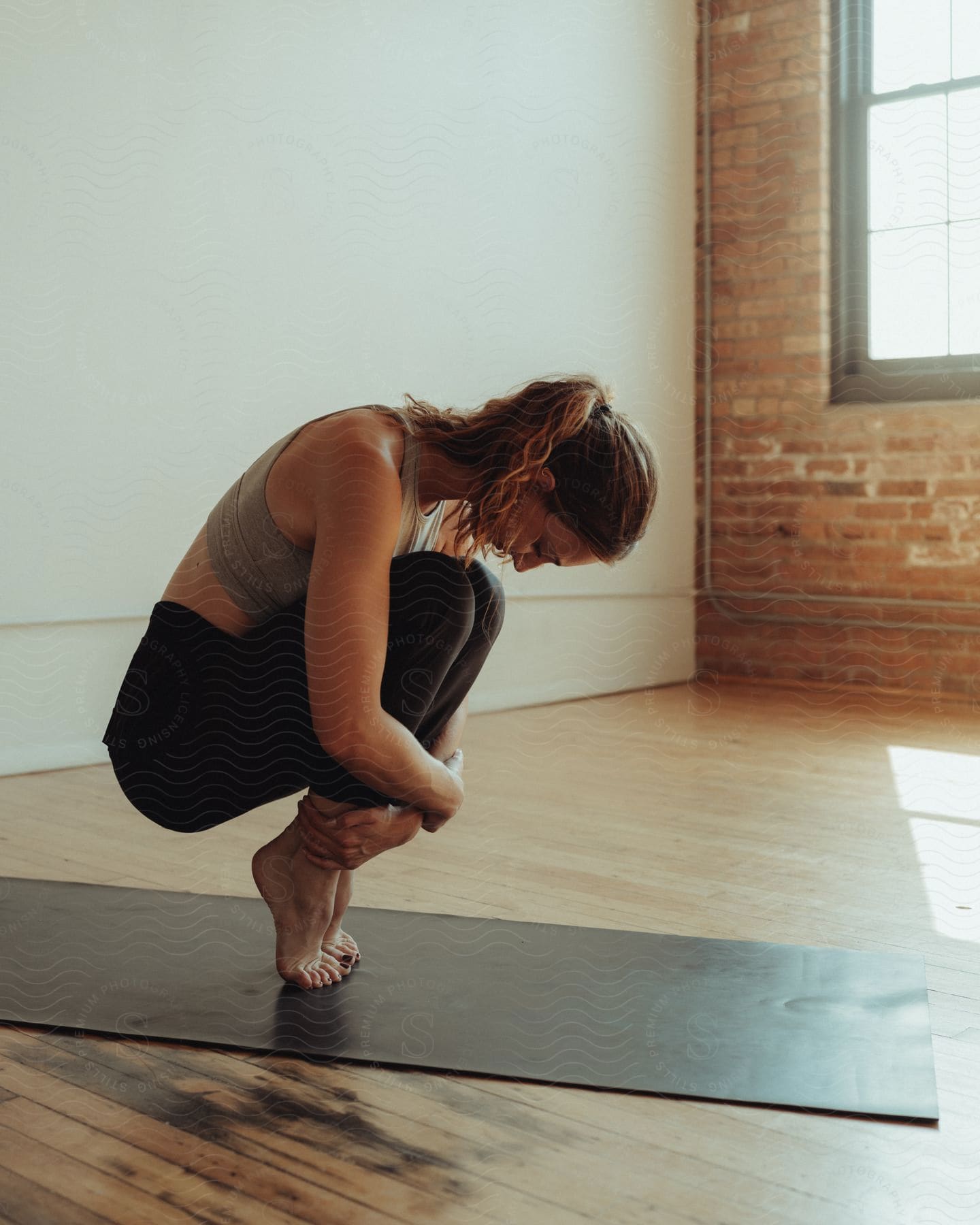 young female doing yoga on a mat indoor at mid-day