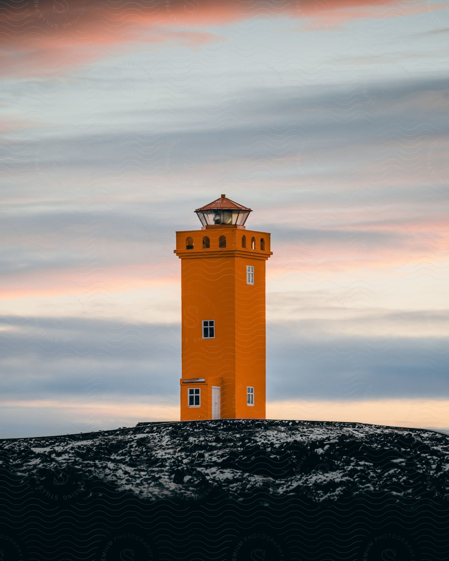 an orange lighthouse sits on a cliff