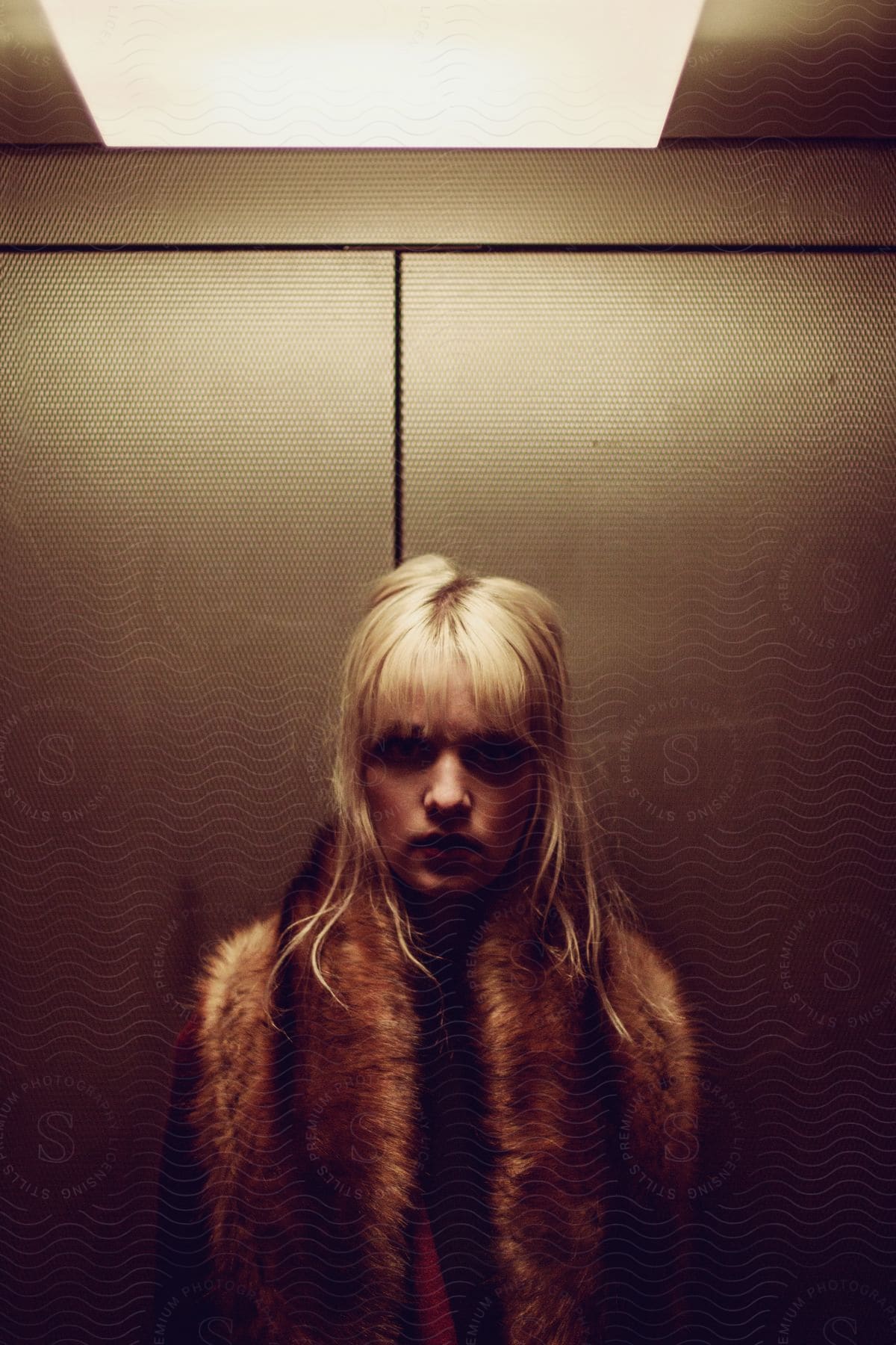 A woman wearing a fashionable vest while standing in an elevator.