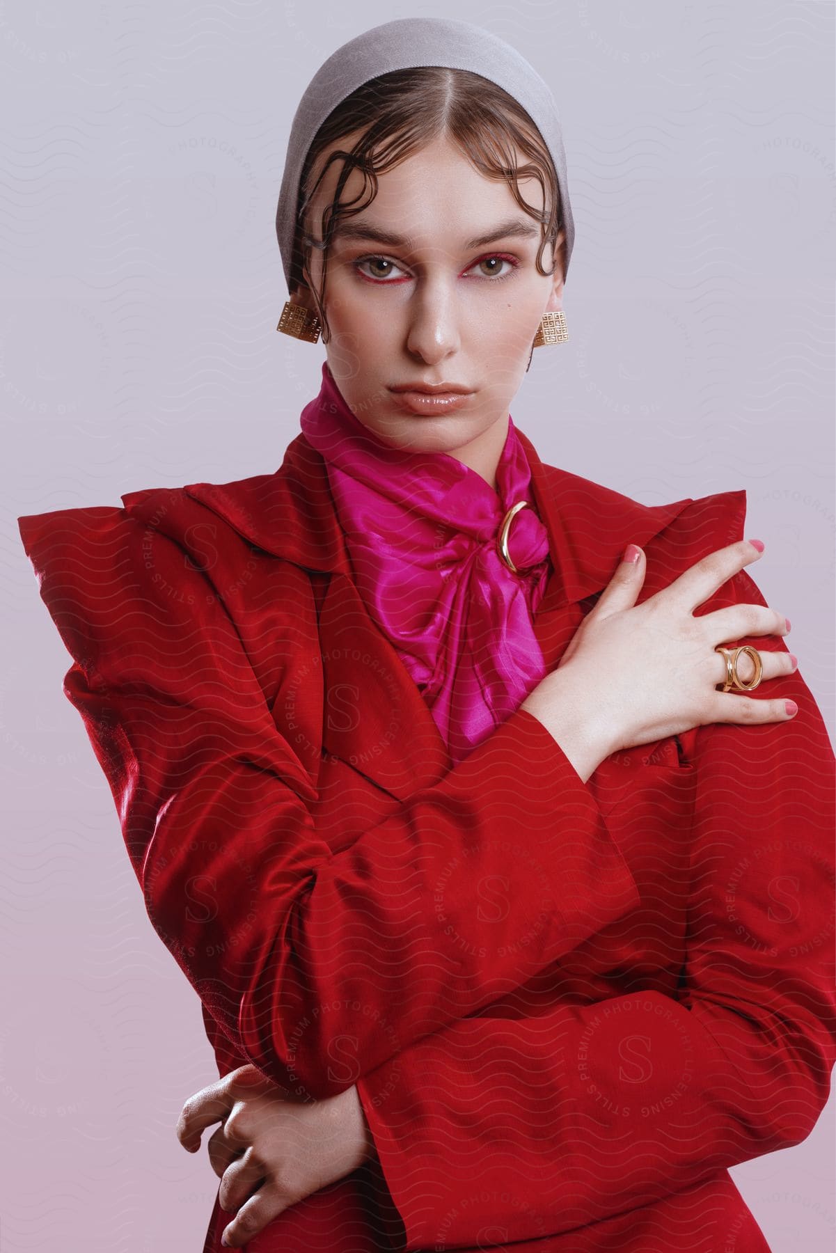 A woman wearing a red suit has her hair and makeup done for a photoshoot.