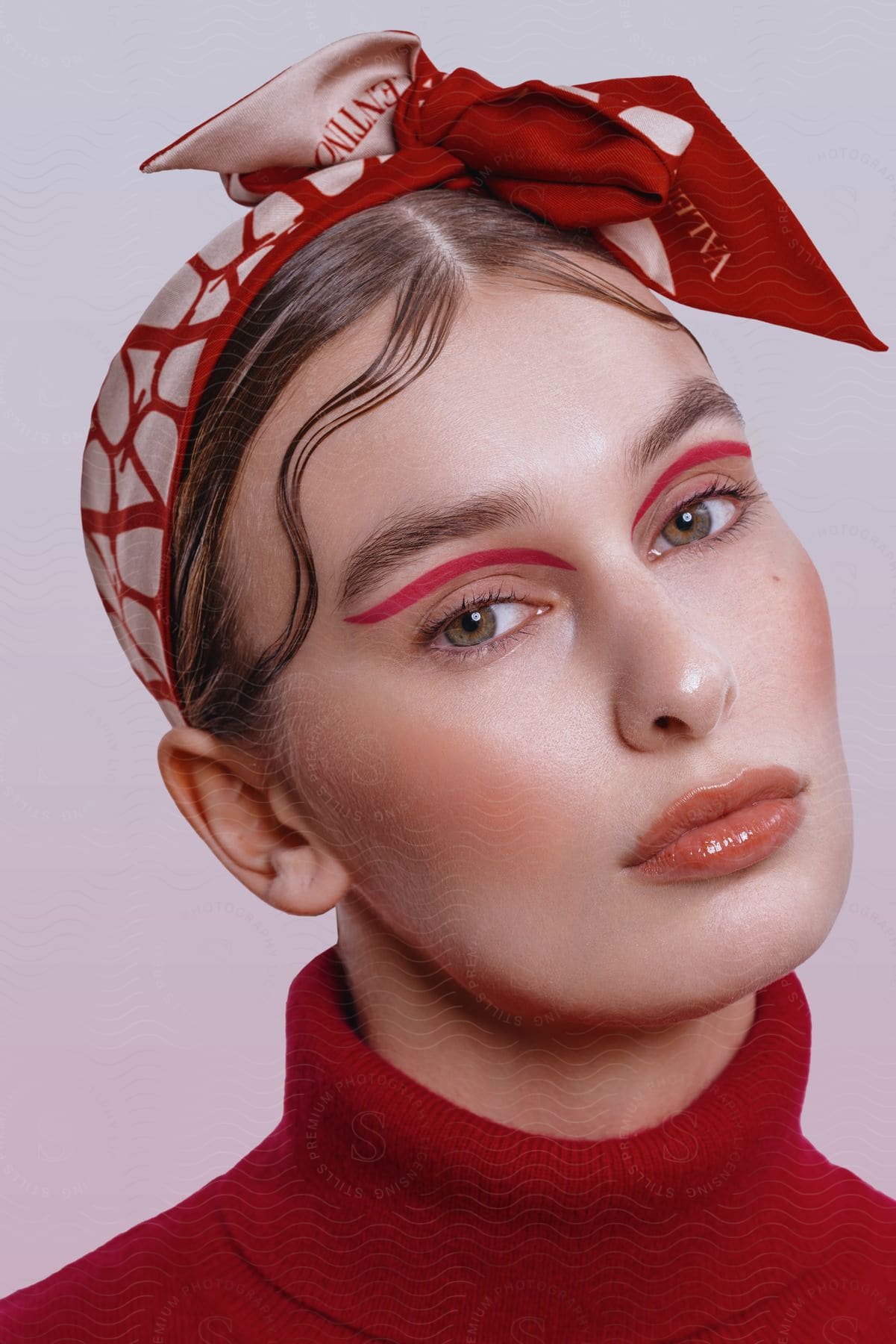 A woman with red makeup, headband and turtleneck on as she looks forward her lips pursed.
