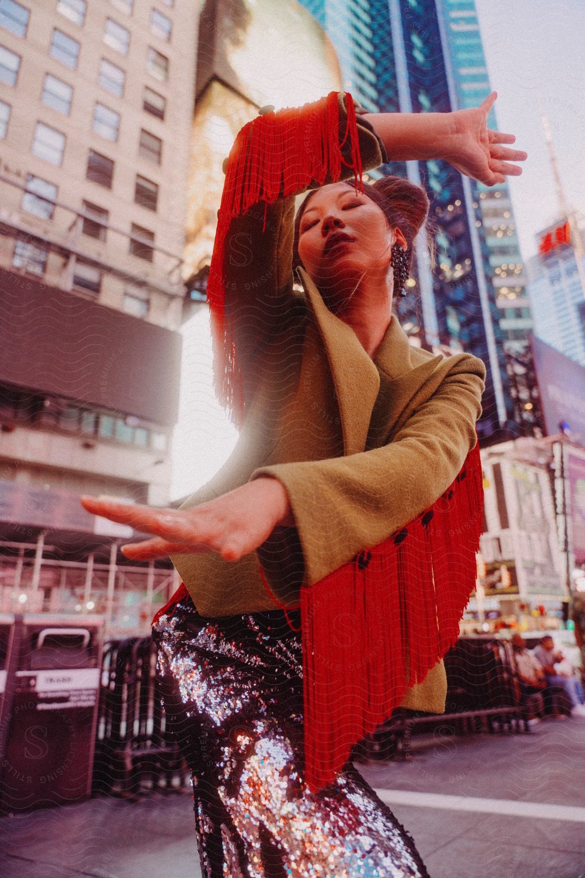 Stock photo of a woman wearing a red fringe jacket is dancing on a downtown street with towers and buildings in the distance