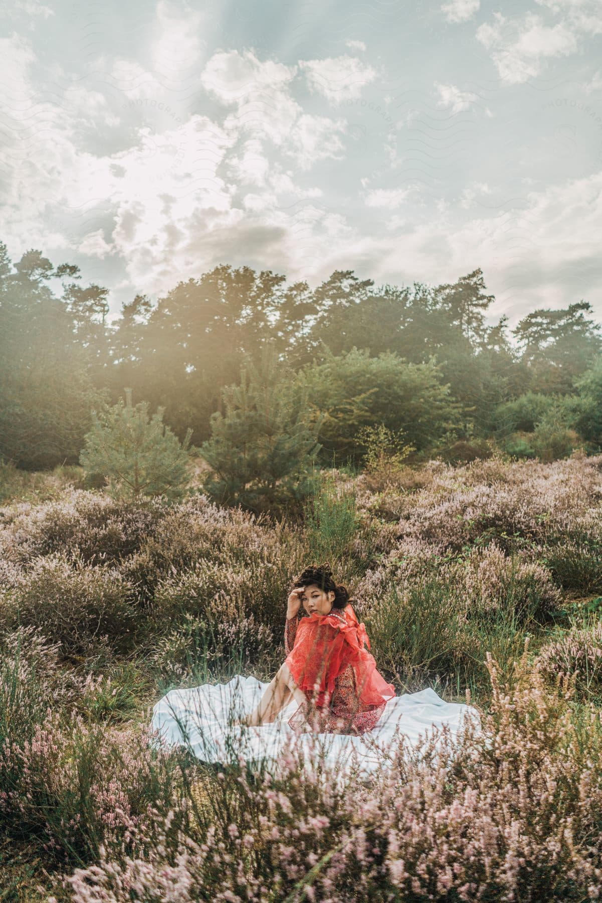 Woman sits over a blanket surrounded by wild flowers