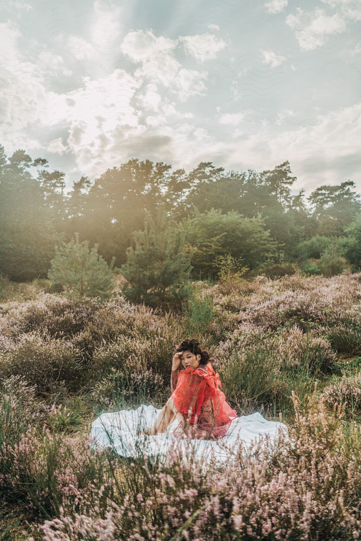 Woman Sits Over A Blanket Surrounded By Wild Flowers